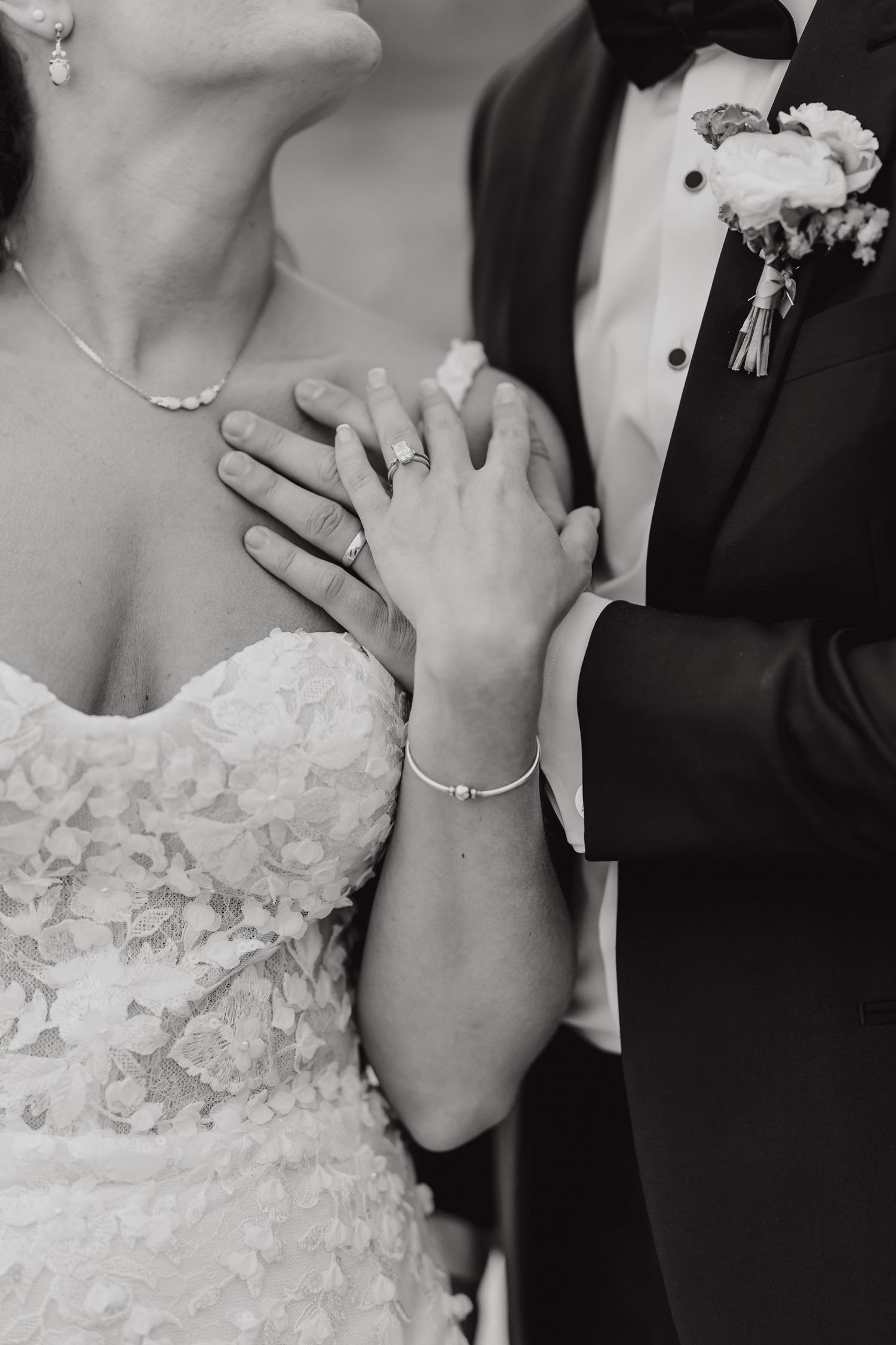 Close-up black and white detail of hands and wedding attire during an intimate moment.