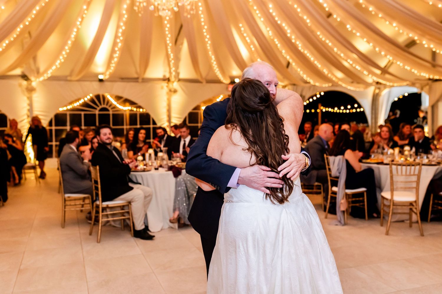 Romantic dance moment during wedding reception in beautifully lit tent venue.