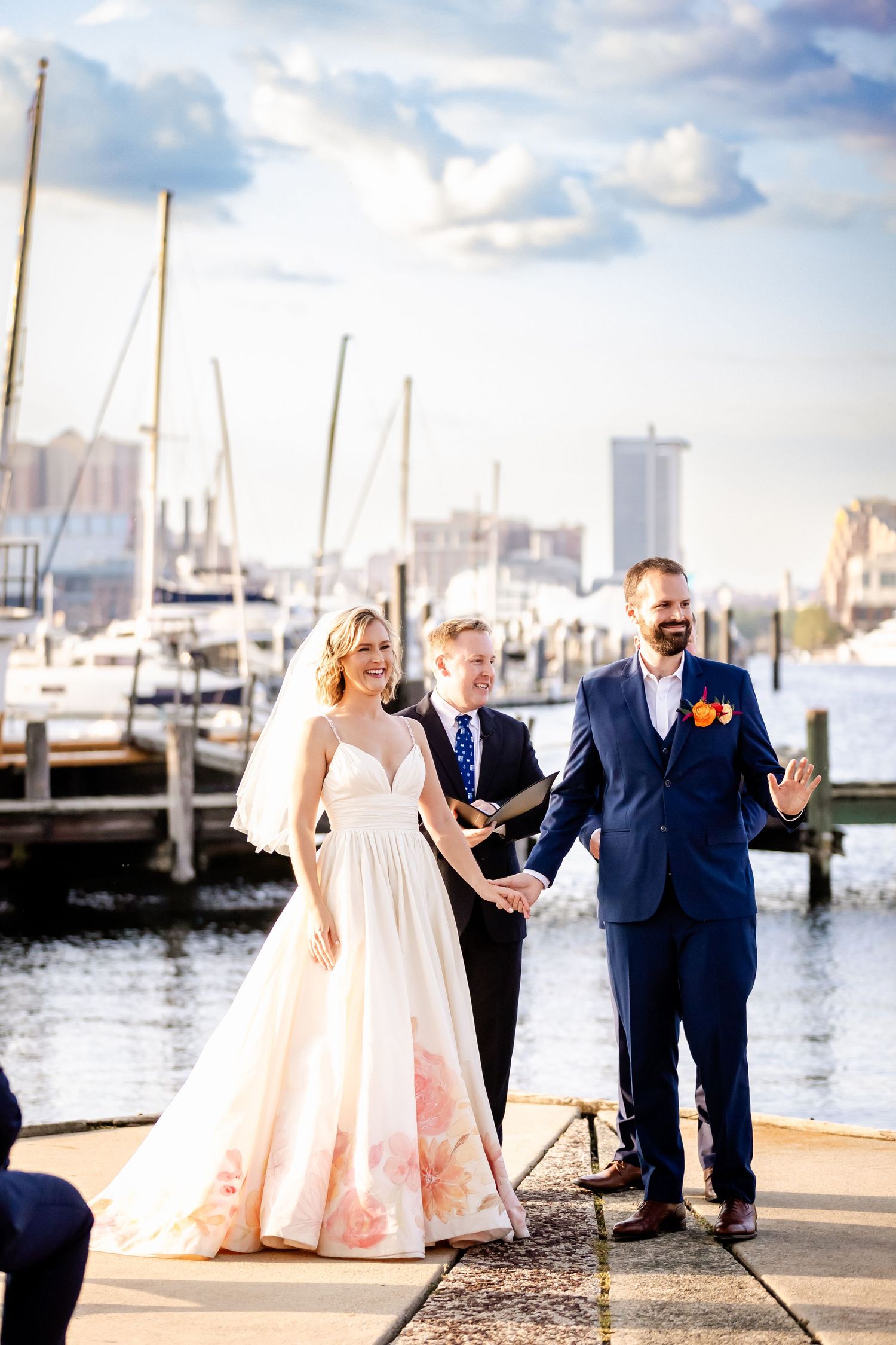Waterfront wedding ceremony at a marina with sailboats in the background.