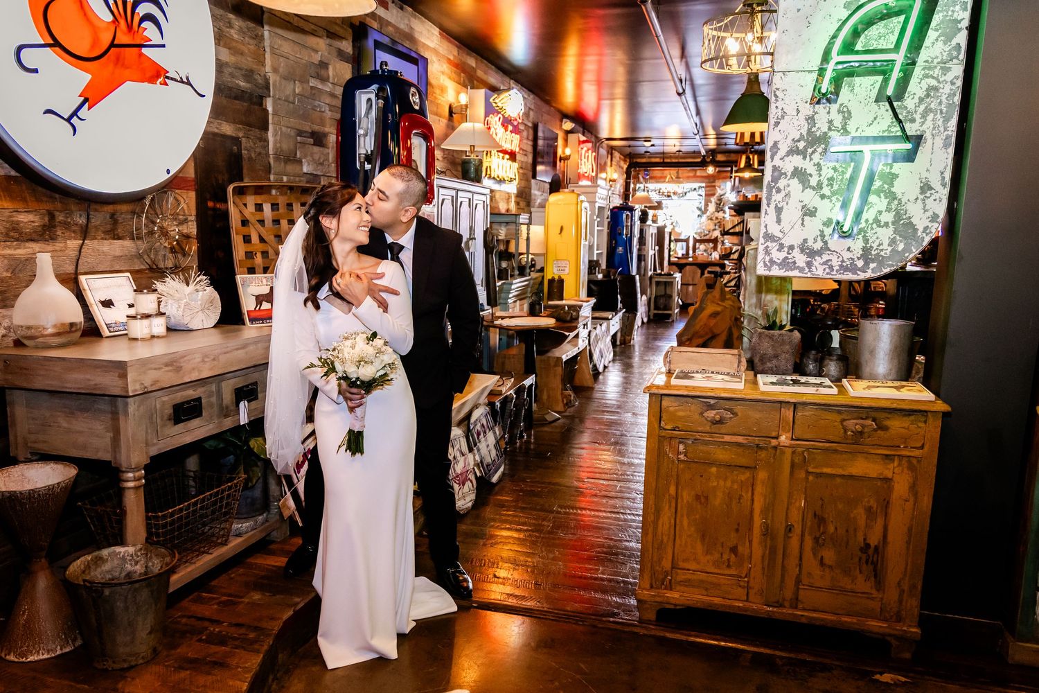 A couple in wedding attire explores an antique shop filled with vintage decor.