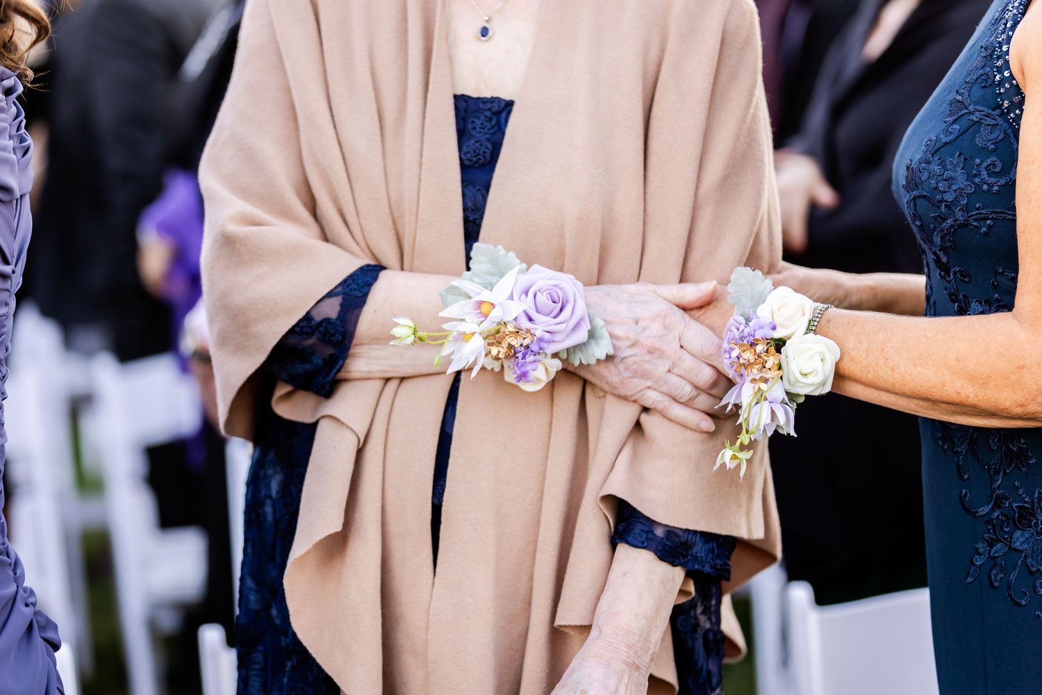 Close-up of delicate wrist corsages with lavender roses and ribbons.