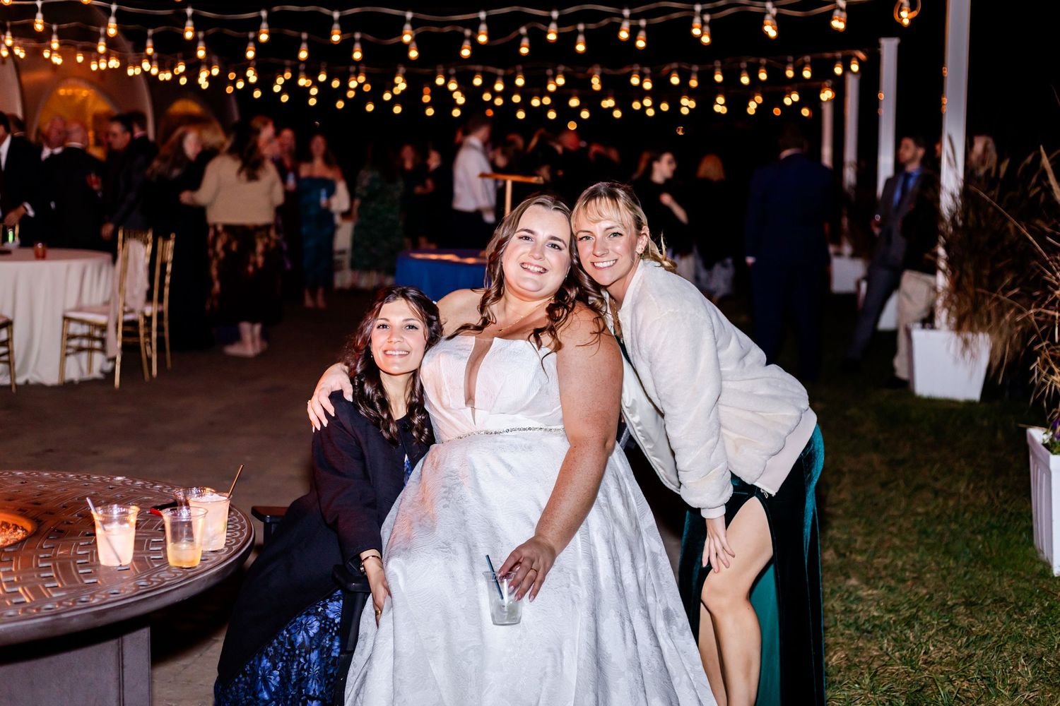 Reception celebration under string lights with guests enjoying evening festivities.