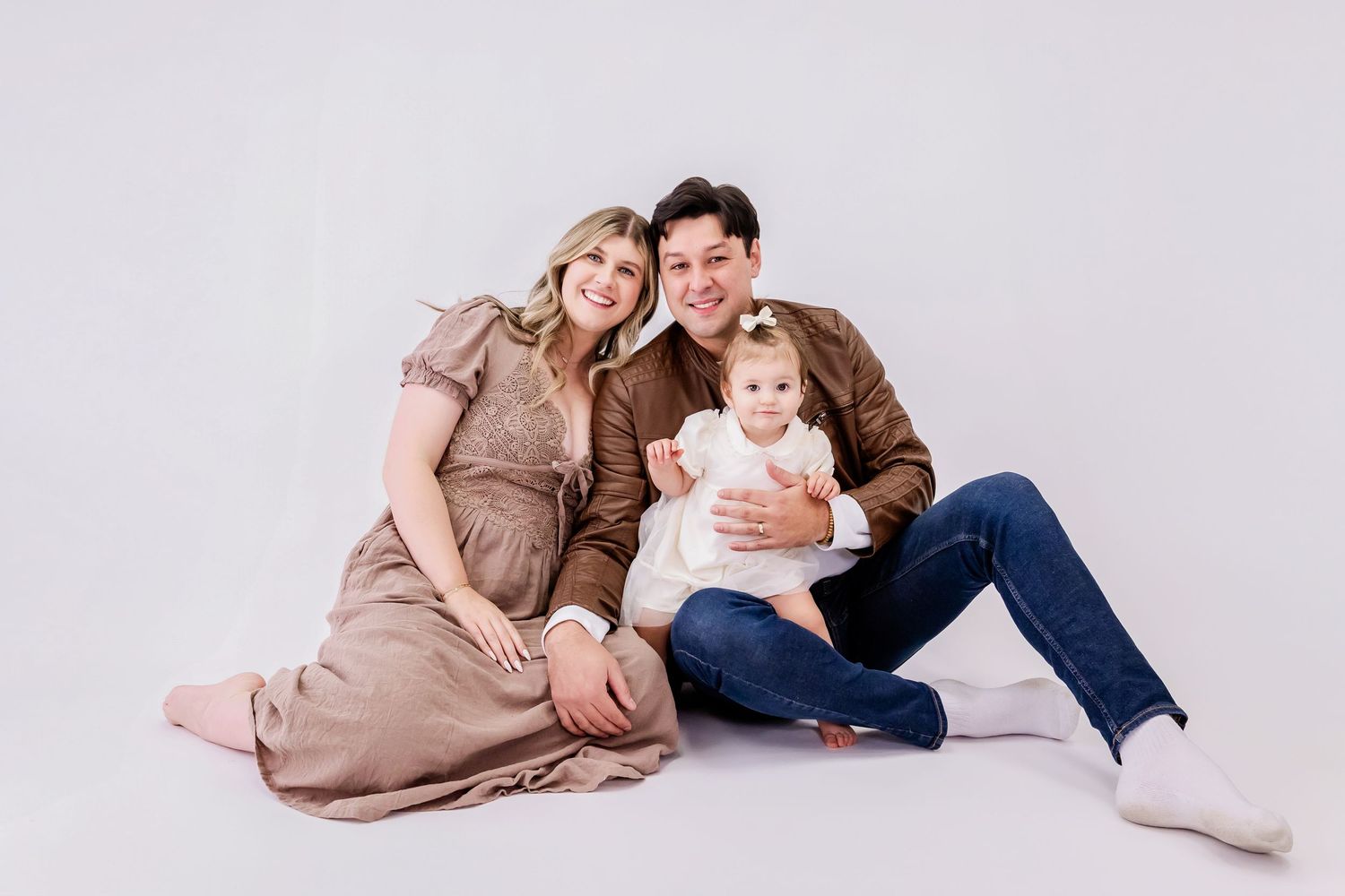 A series of maternity photos showing a couple in casual attire posing together on a light backdrop.
