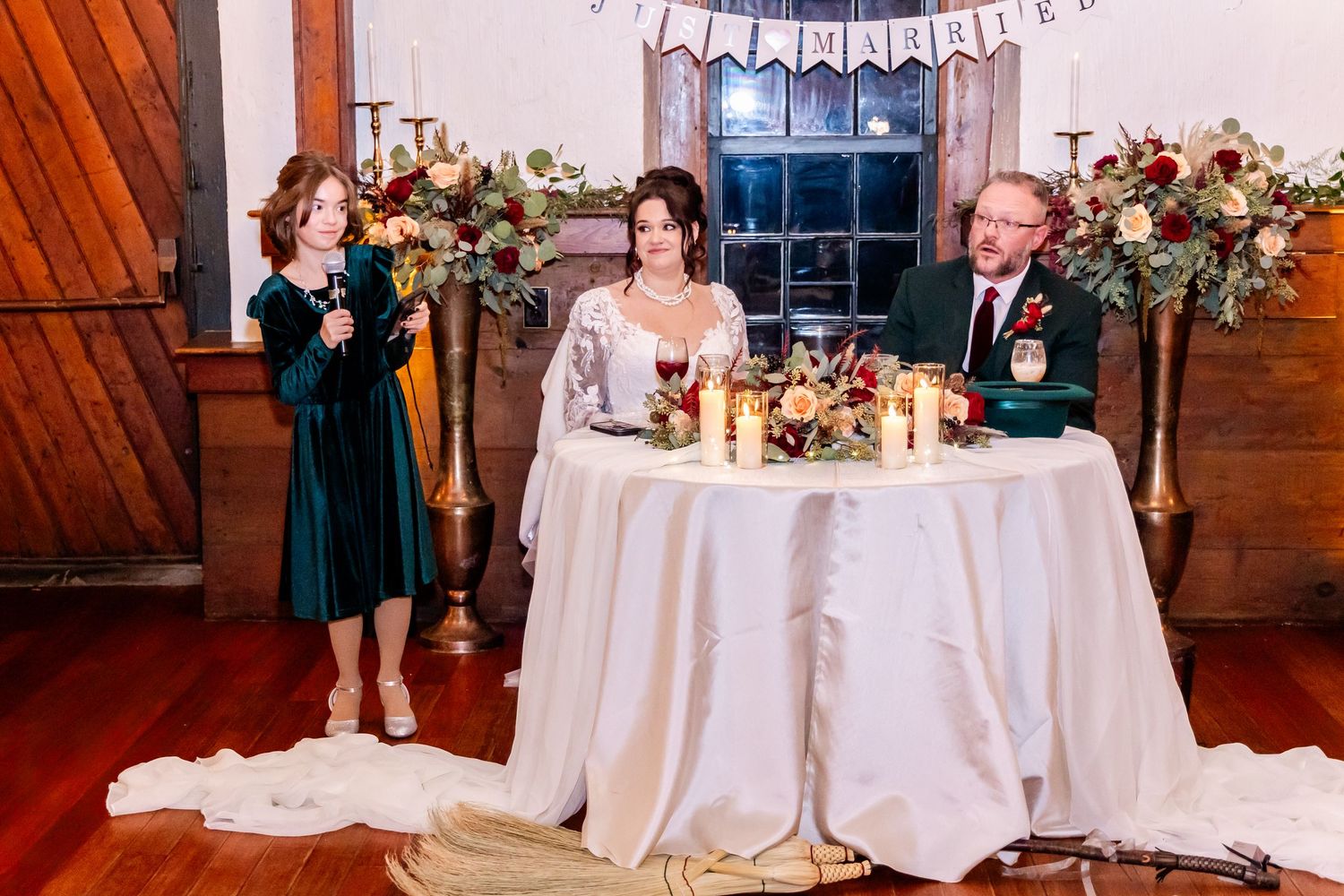 Wedding reception table setting with floral arrangements and candlelight in rustic venue.