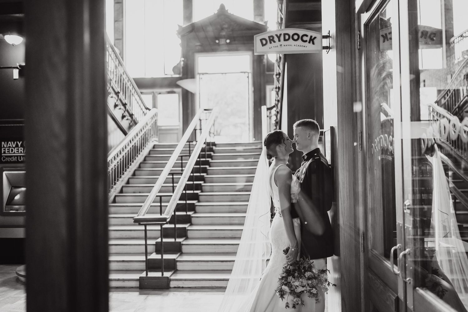Black and white wedding photos captured in an elegant building hallway.