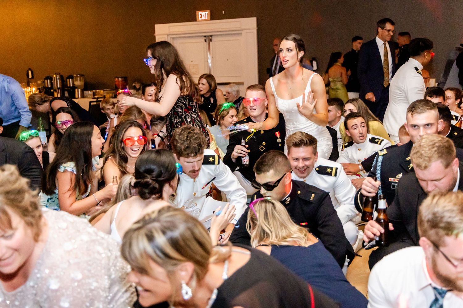 Crowded dance floor with wedding guests enjoying the celebration in dim lighting.
