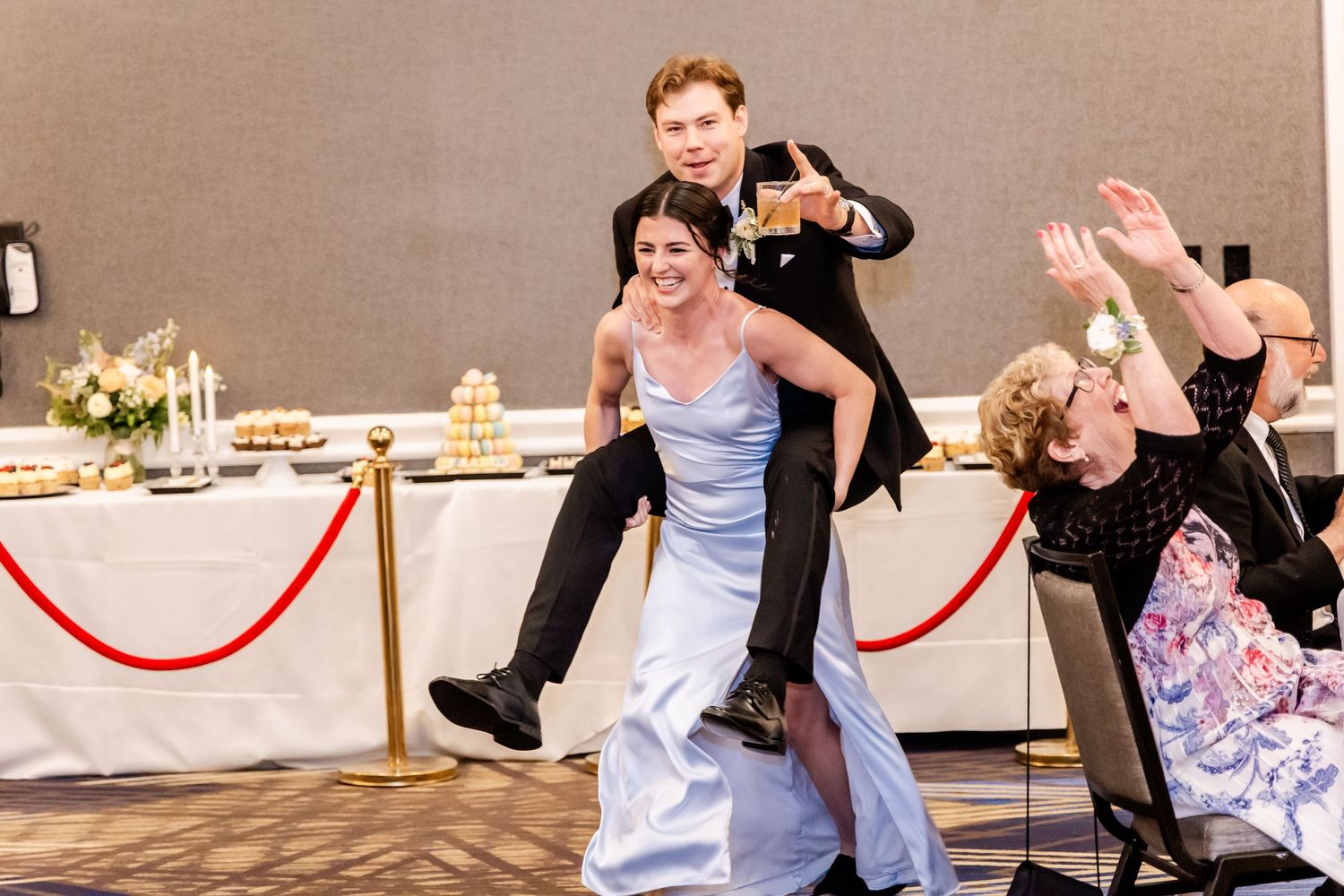 Wedding reception guests dancing and celebrating with red velvet ropes visible in the background.