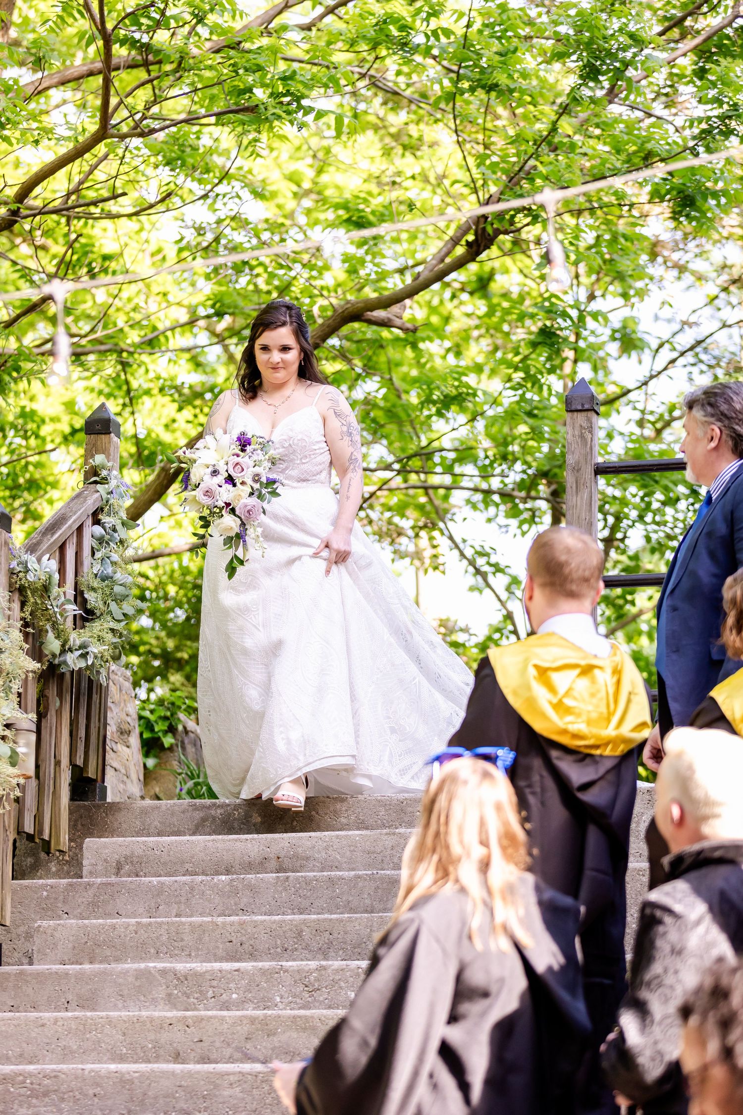Wedding party in mix of formal wear and wizard robes gathers on decorated stone stairs.