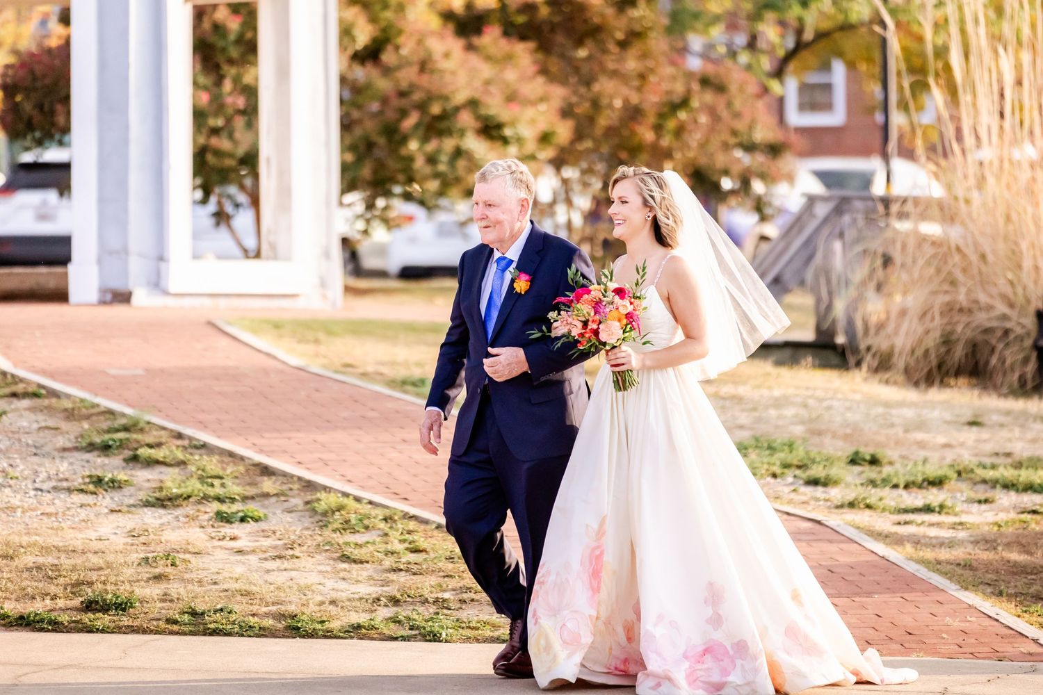 Wedding couple walking down a brick pathway on a sunny afternoon.