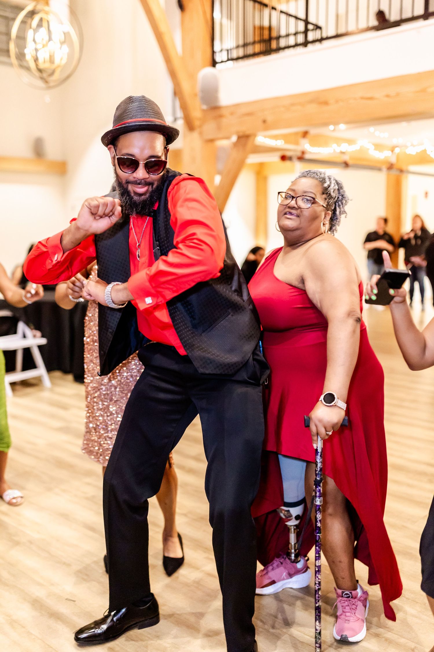 A guest in a red blazer dances enthusiastically at a wedding reception.
