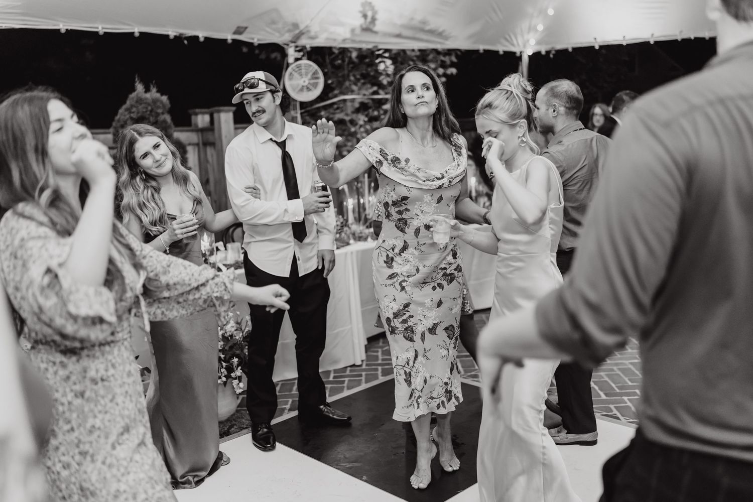 Black and white photo of wedding guests dancing and celebrating at a reception party.