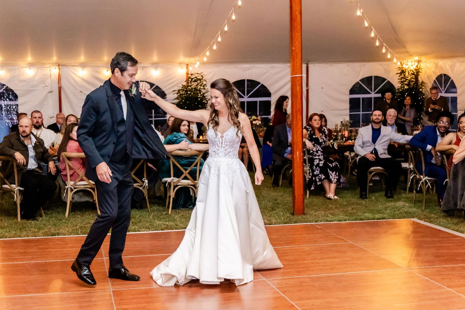 Wedding reception dance floor with string lights and wooden beams creating a warm atmosphere.