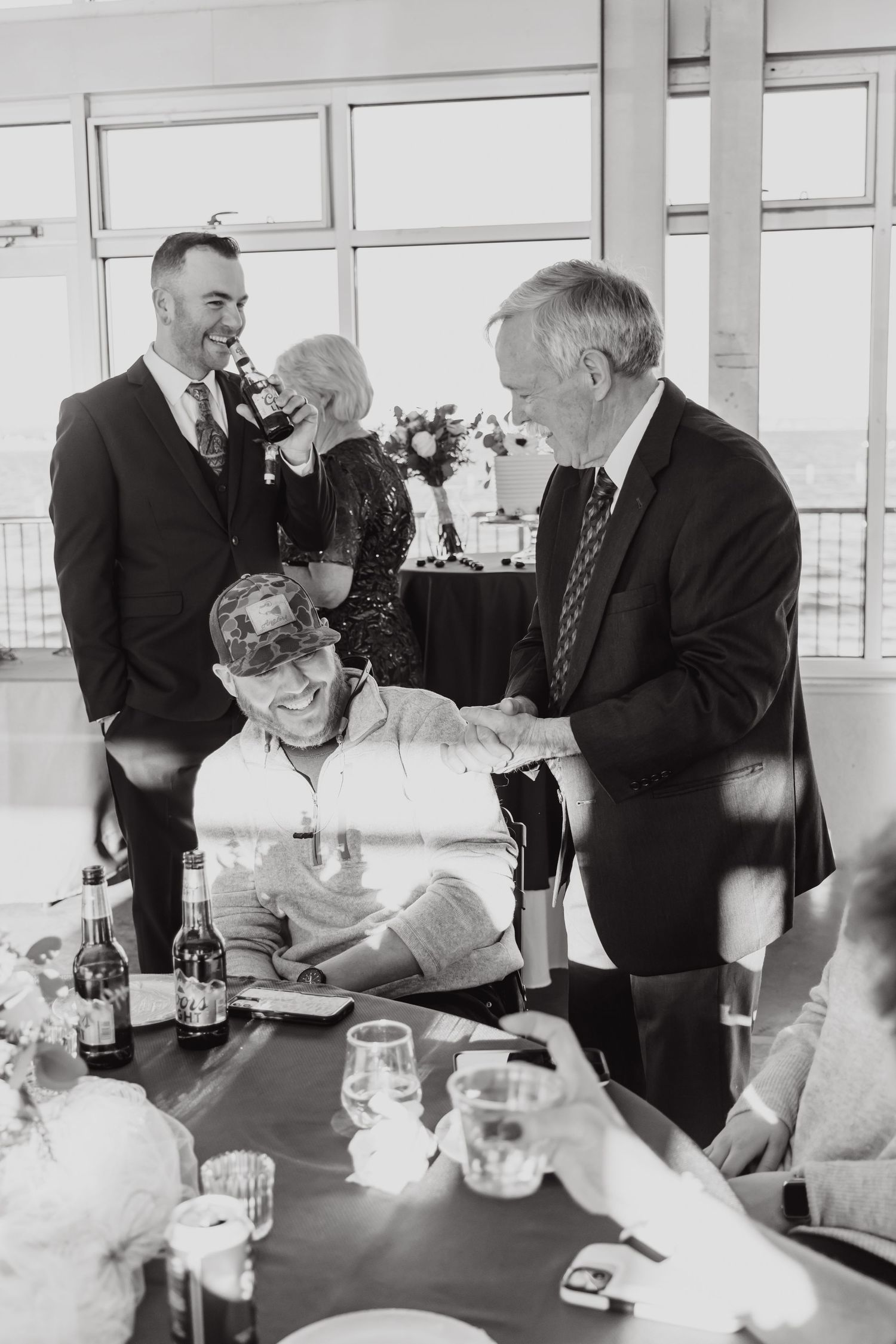 Black and white photo of wedding reception guests socializing at dining table.