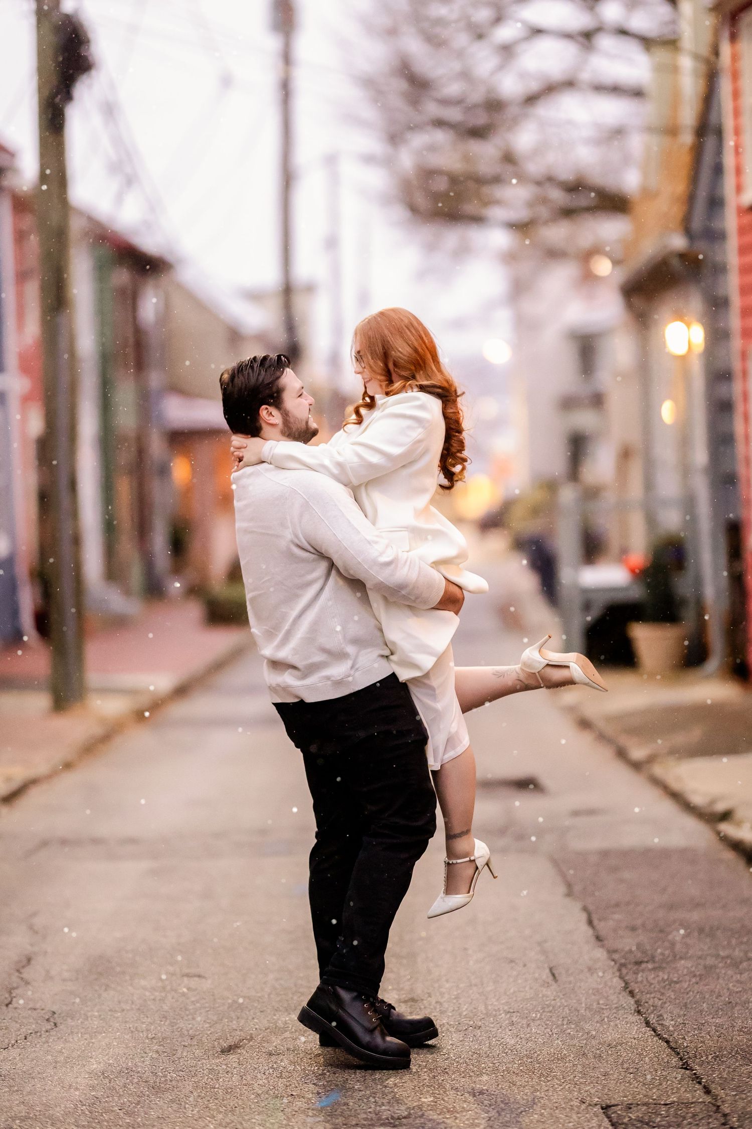 A couple dances together on a tree-lined street at dusk, creating a romantic silhouette against the bokeh lights.