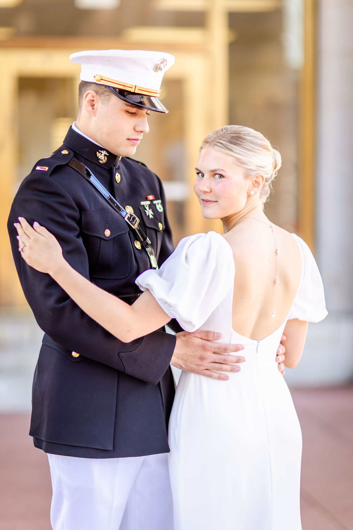A Marine in dress uniform and bride in white dress share an intimate dance moment at their wedding celebration.