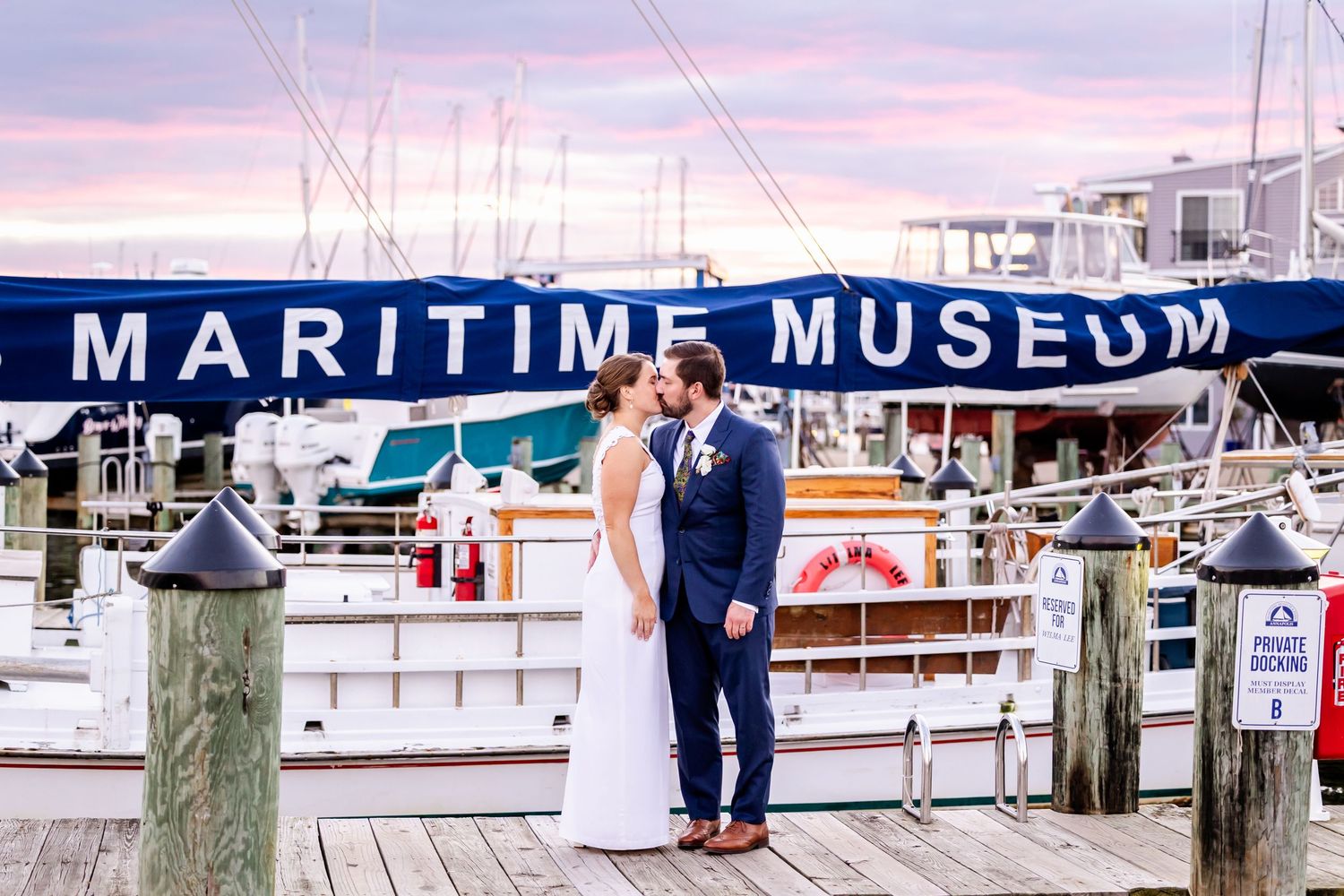 Couple sharing a kiss on a wooden dock at the Maritime Museum at dusk.