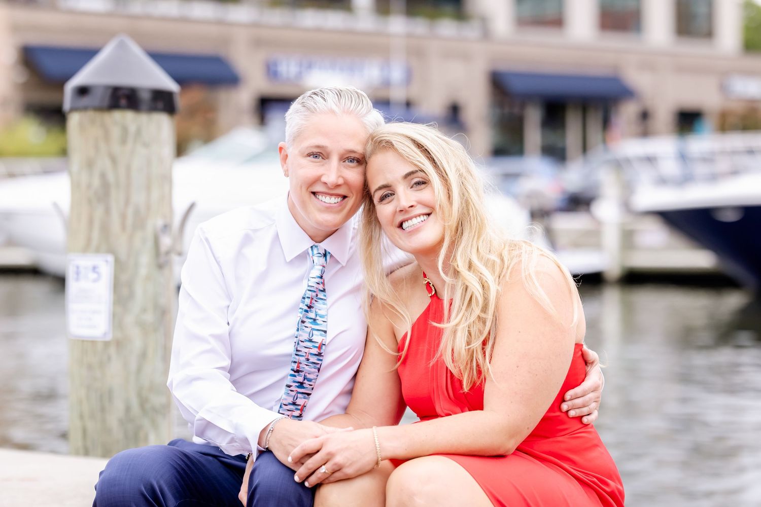 A couple shares romantic moments on a wooden dock by the water during an engagement photoshoot.