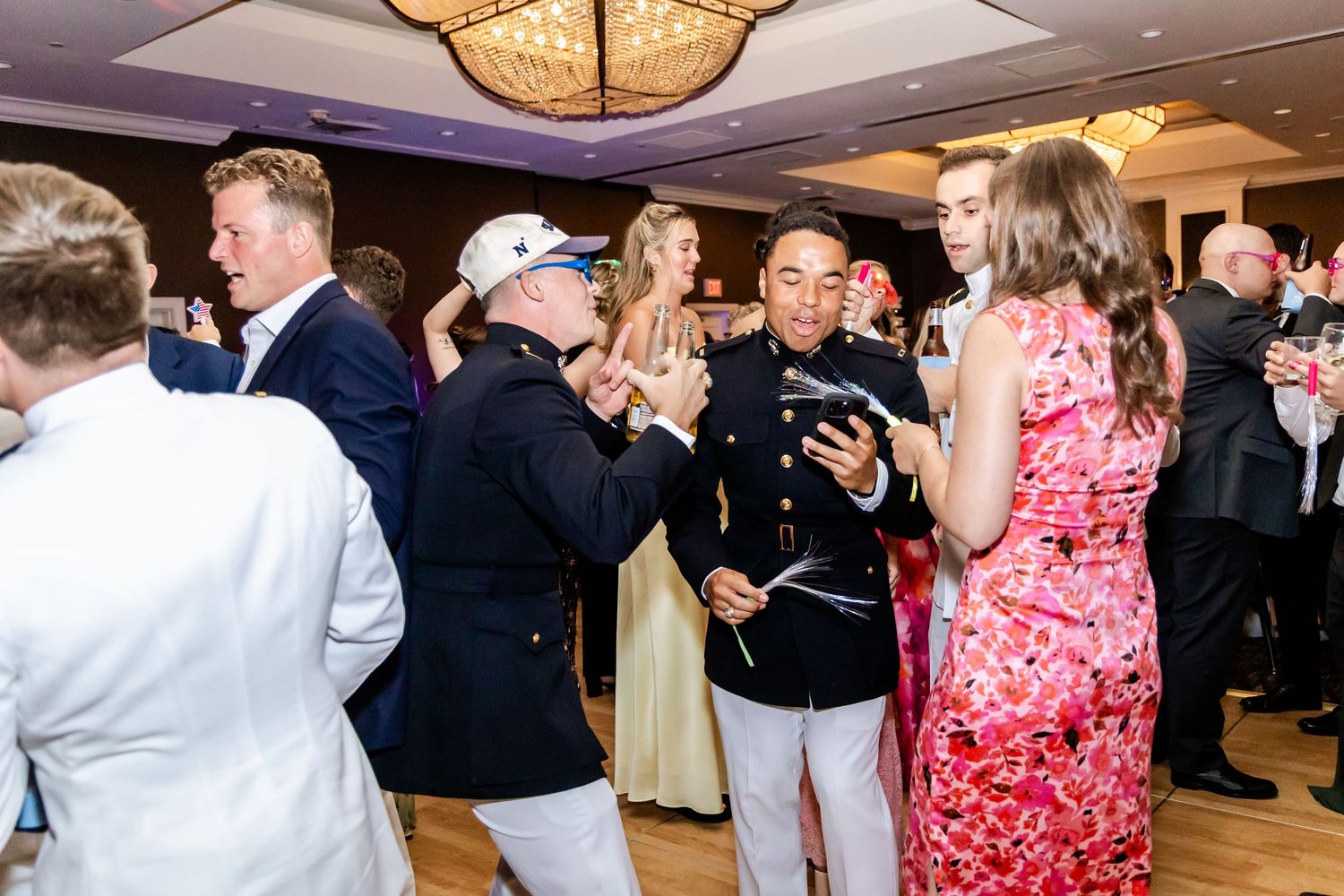 Wedding reception dance floor filled with guests celebrating under elegant chandeliers.