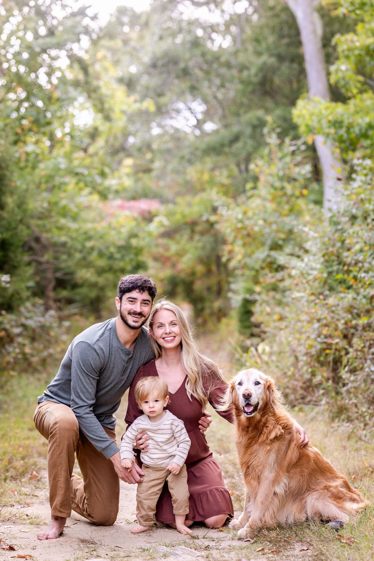 Natural outdoor family portraits with golden retriever dog among autumn trees.