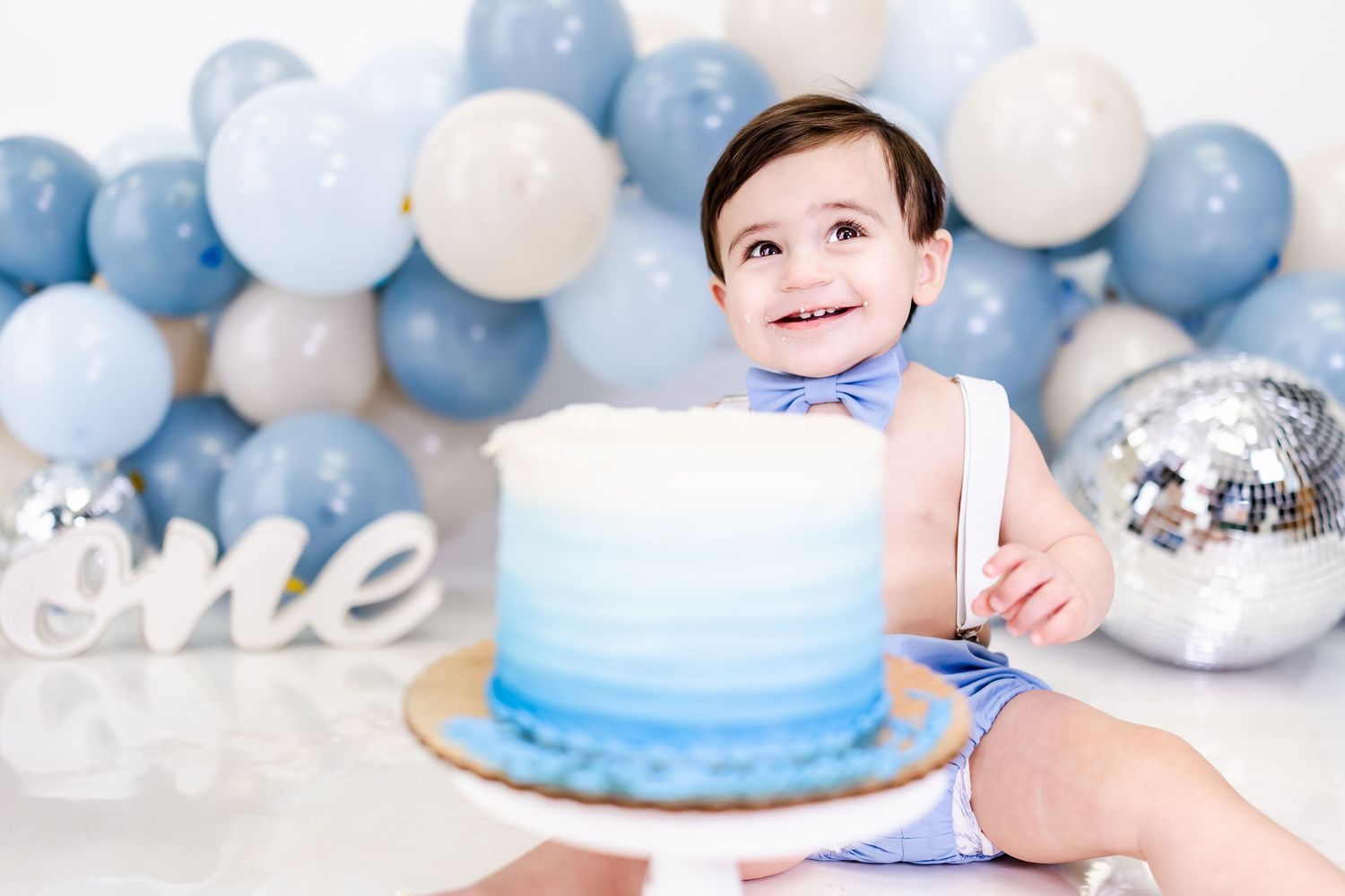 Baby's first birthday celebration with blue and white balloon decorations.