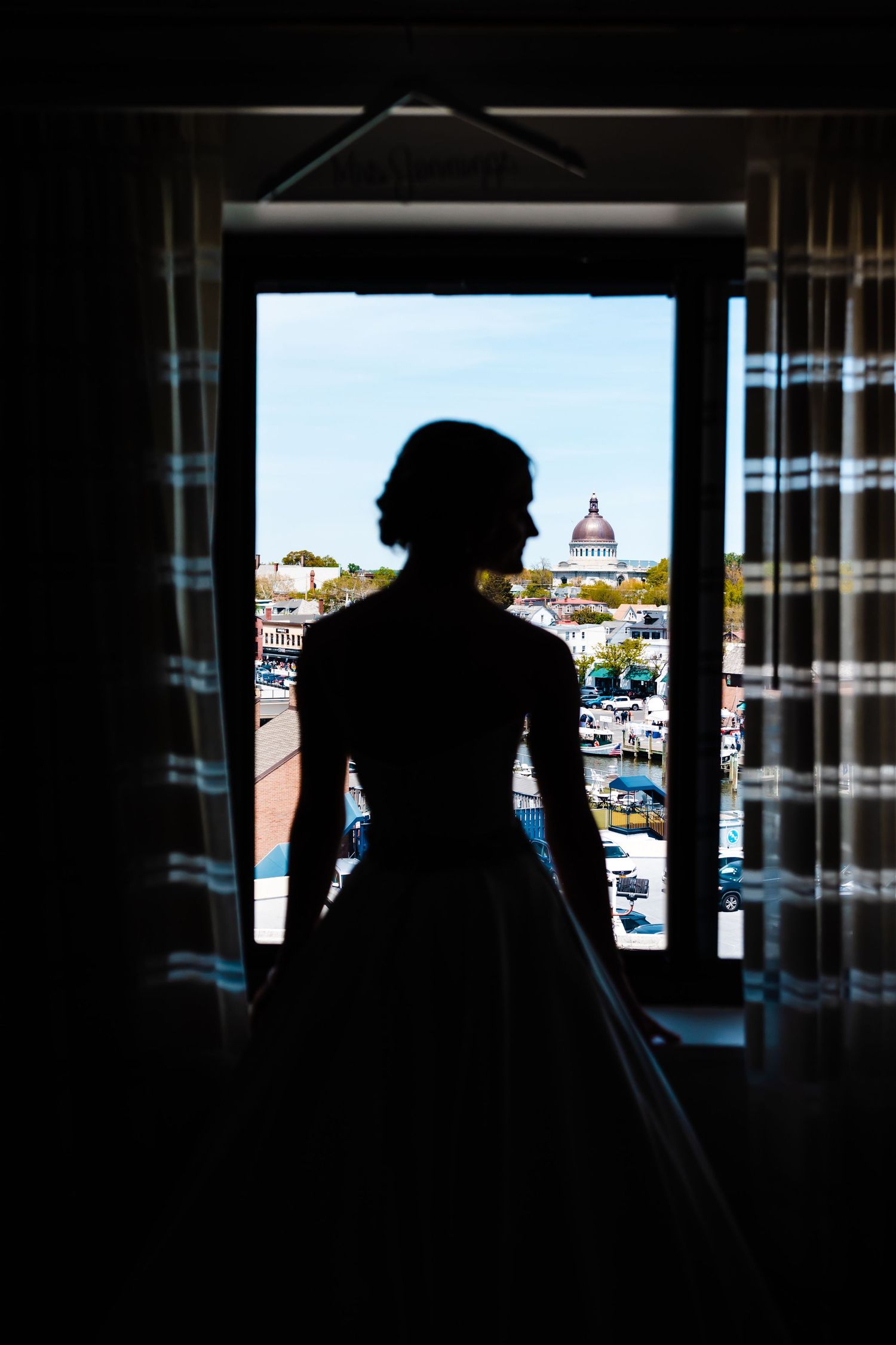 A silhouette in a dress stands at a window overlooking Florence, Italy with the cathedral dome visible in the distance.