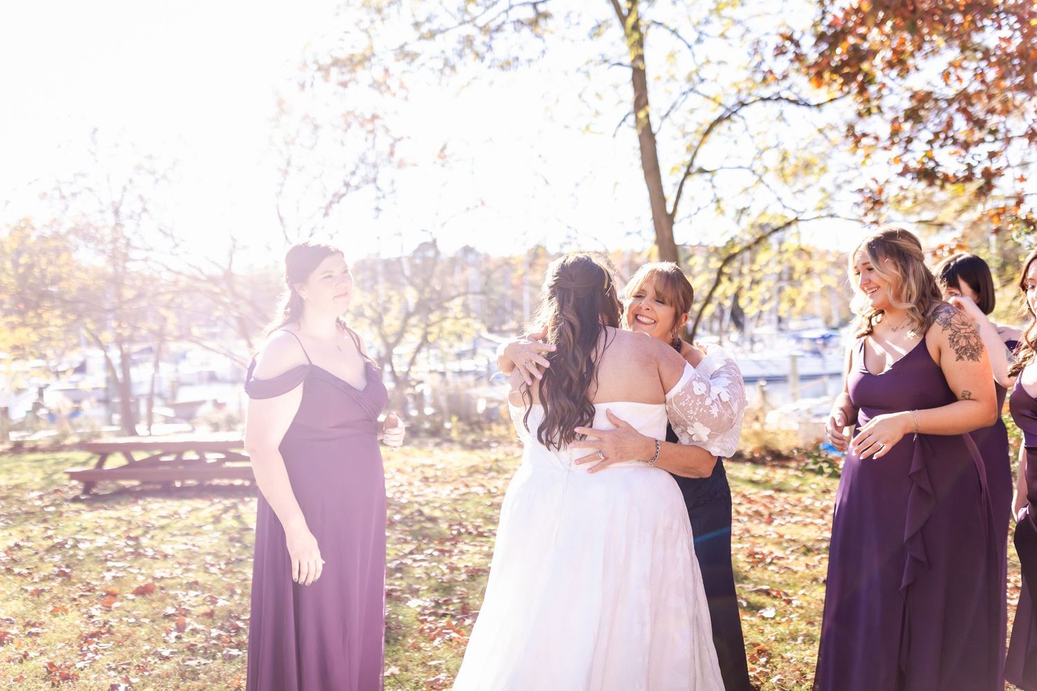 Wedding party gathers for intimate moment among autumn trees during ceremony.