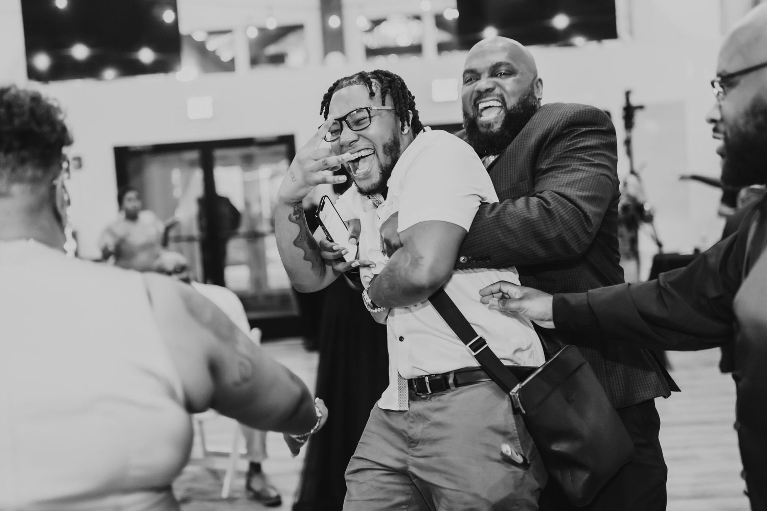 A black and white photo capturing a lively moment at a celebration with people dancing and laughing.