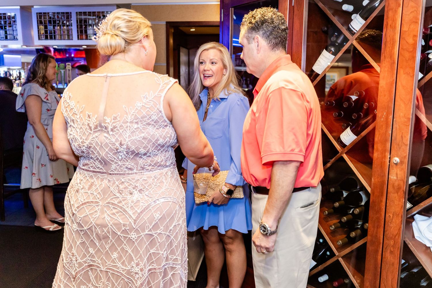 People gathered for a celebration in a restaurant with wine racks visible in the background.