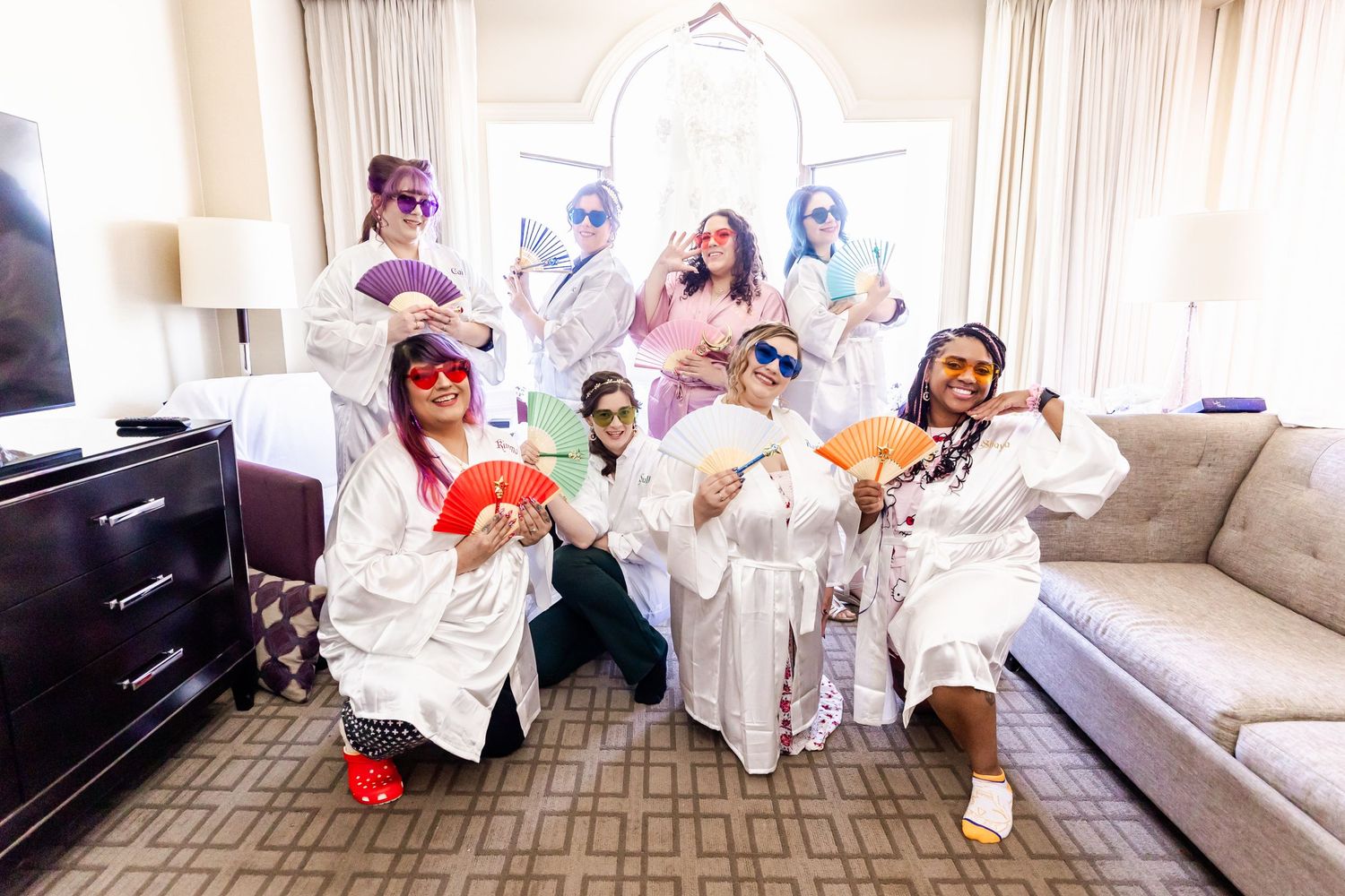 Wedding party in white robes making silly poses in a hotel room.
