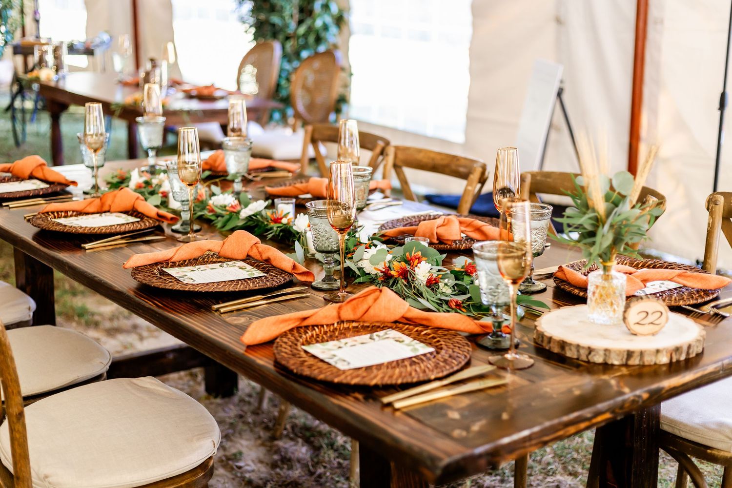 Rustic wedding reception tables decorated with wooden chargers and natural greenery.