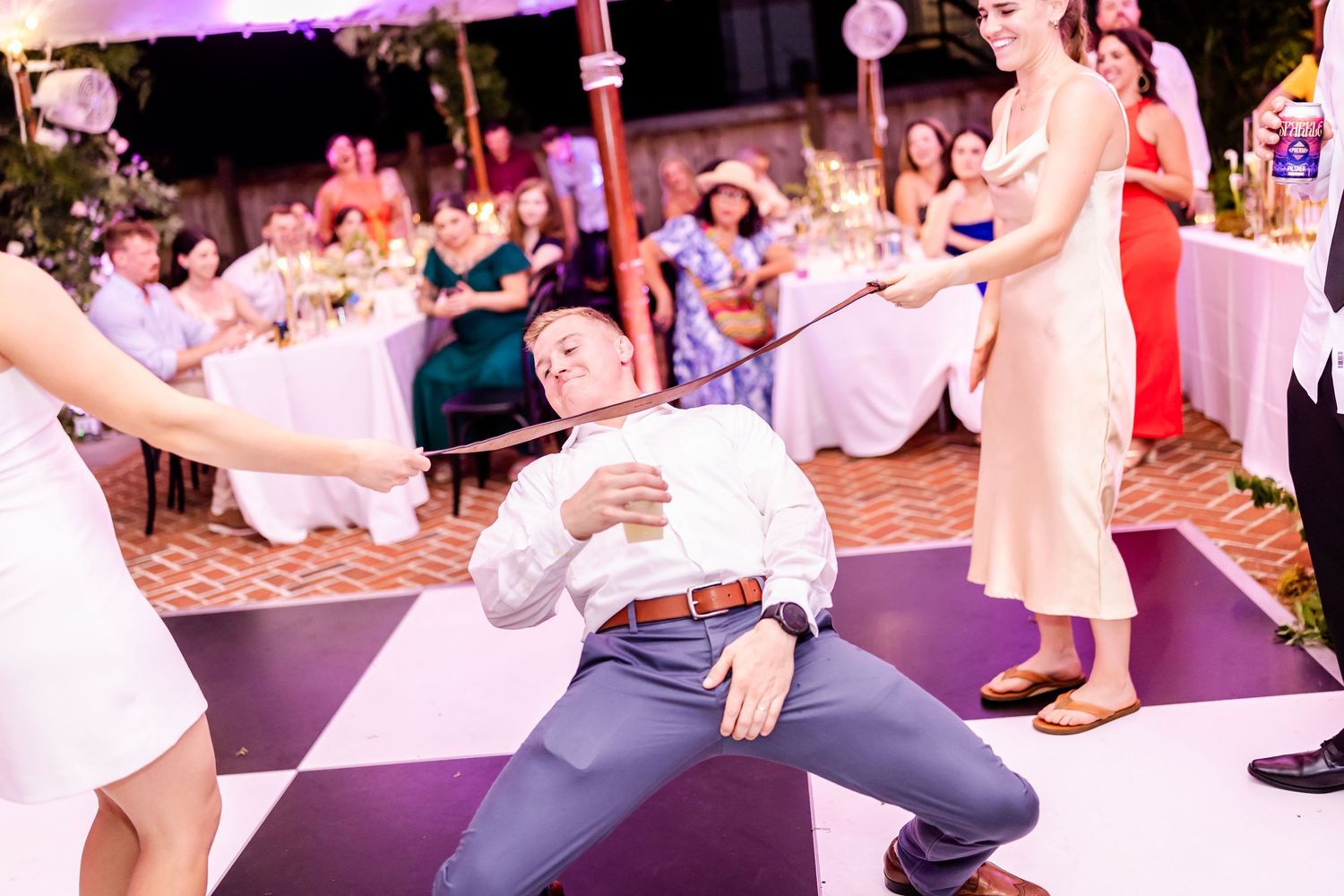 Wedding guests dancing and having fun on a checkered dance floor at a lively reception celebration.