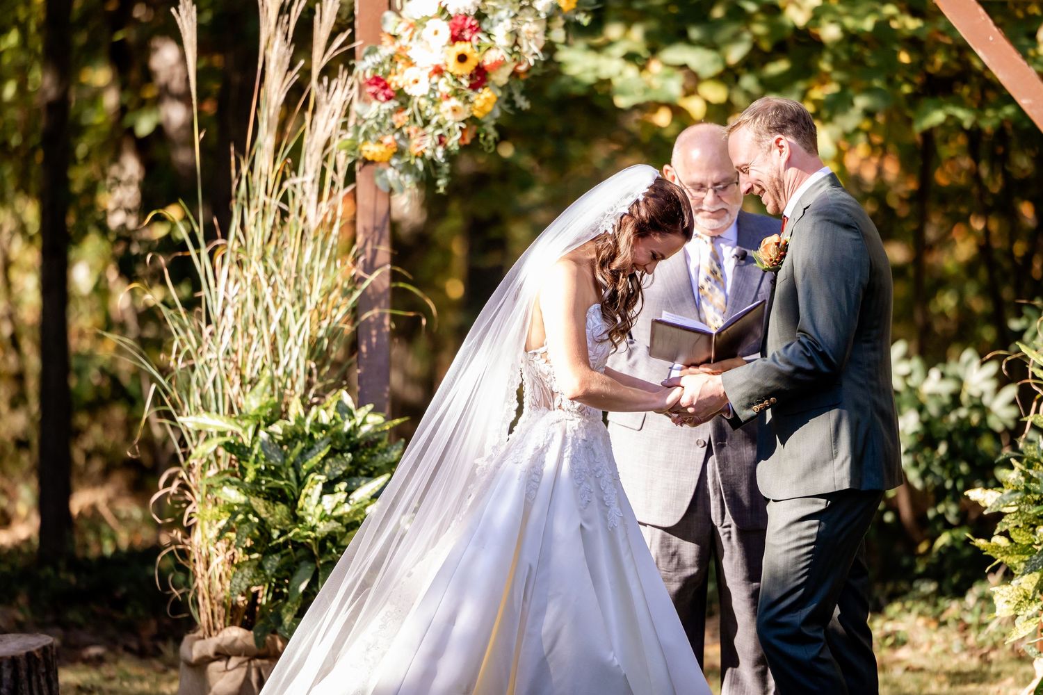 Newlyweds share romantic moment in outdoor autumn setting with golden sunlight.