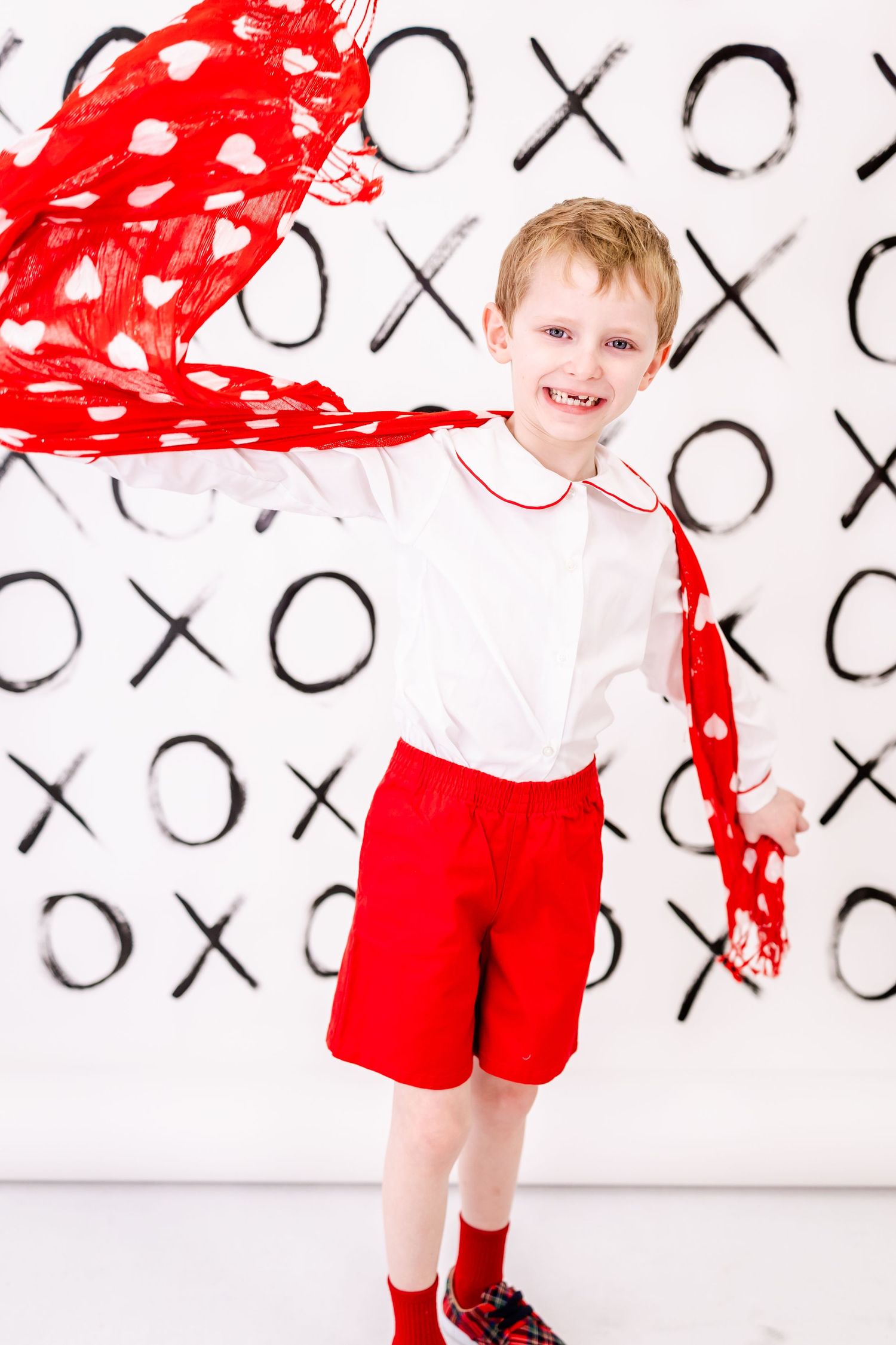 Red and white themed photo with white background featuring X and O patterns and dramatic red paint splatter effect.