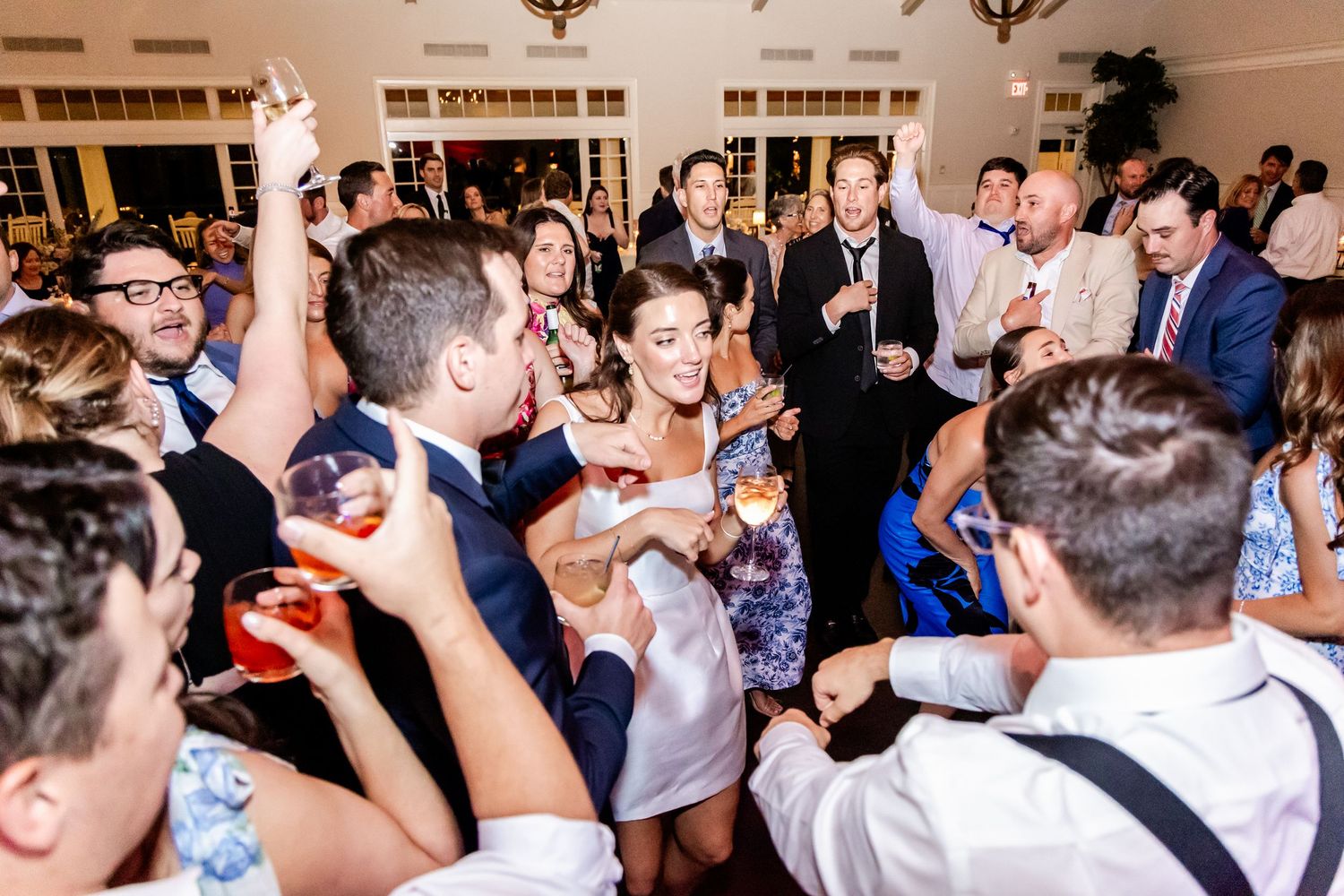 Energetic crowd of wedding guests dancing and celebrating on a packed dance floor.