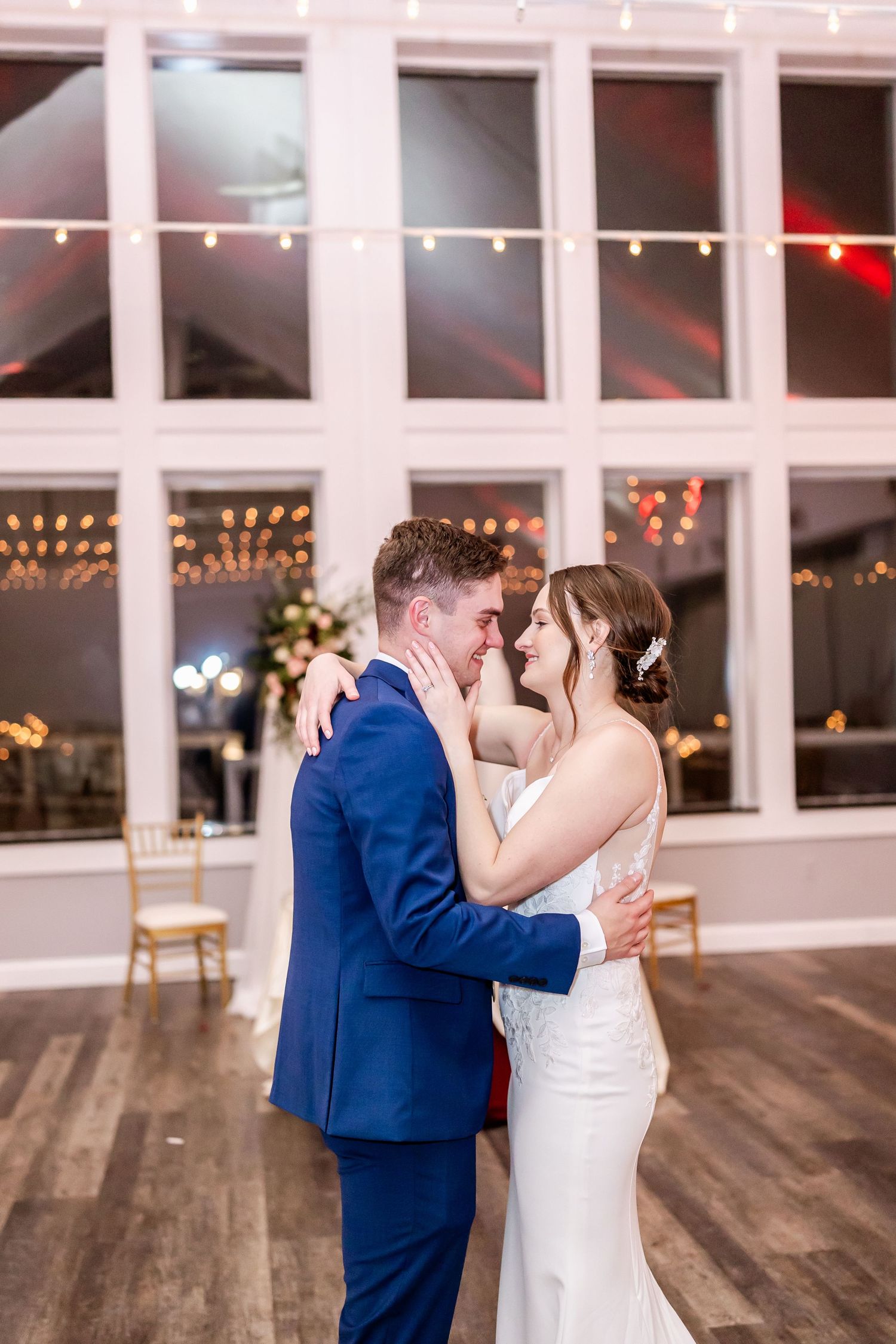 Romantic first dance sequence between couple in blue suit and white dress on wooden dance floor.