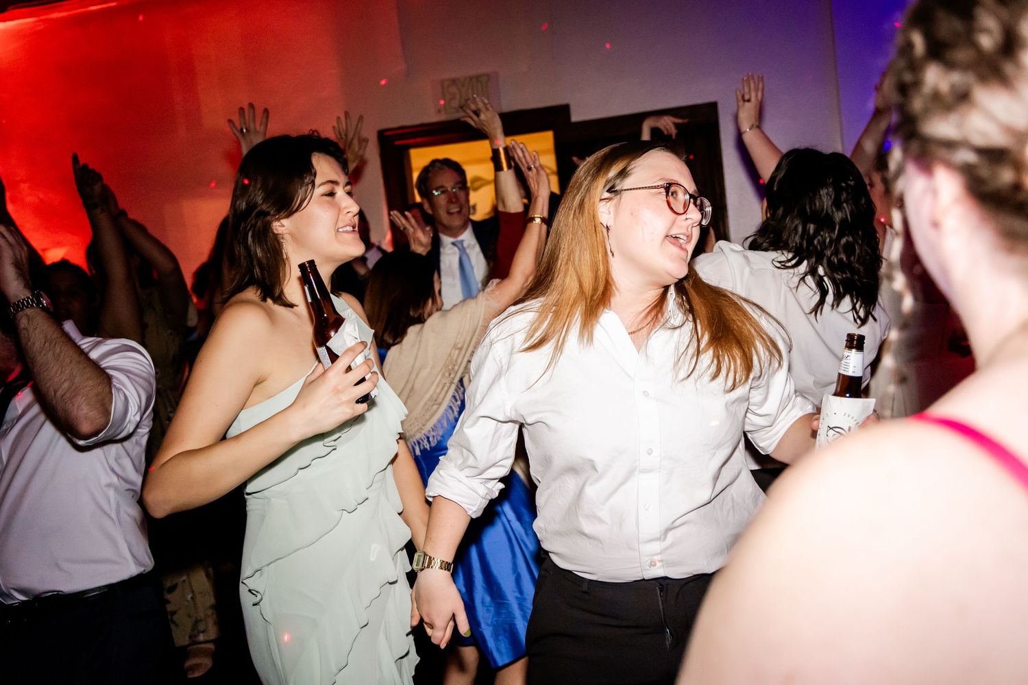 People dancing and having fun at a party with colorful mood lighting in the background.