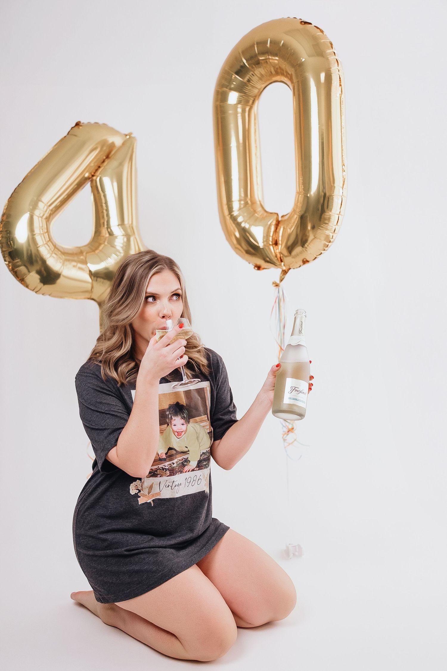Casual portrait session with gold balloon numbers and snacks against white background.