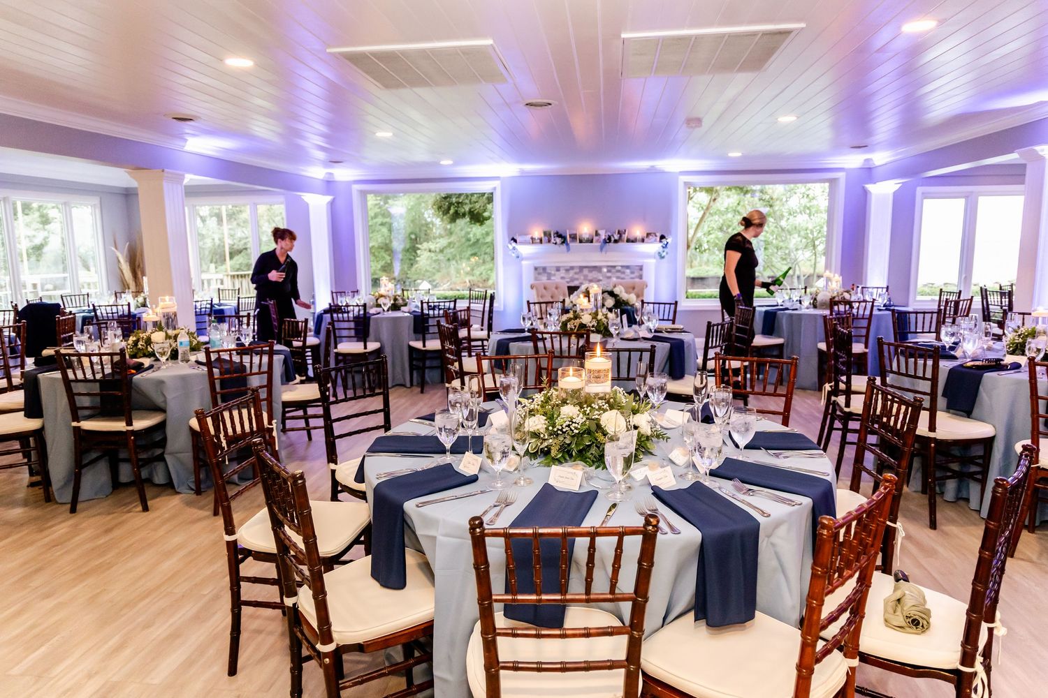Elegant wedding reception hall with purple lighting and mahogany chairs.