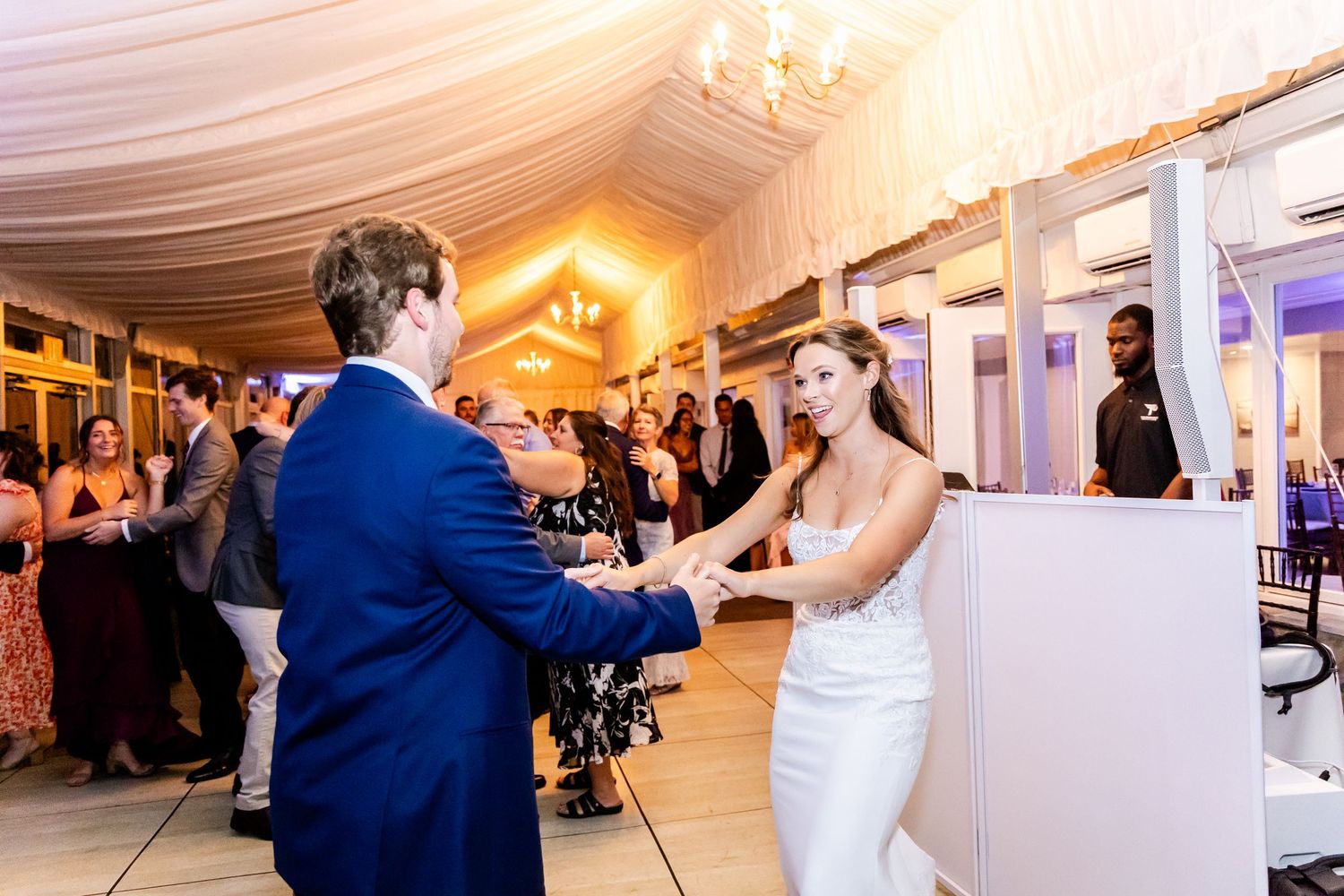Couple dancing together at wedding reception in elegant white tent venue.