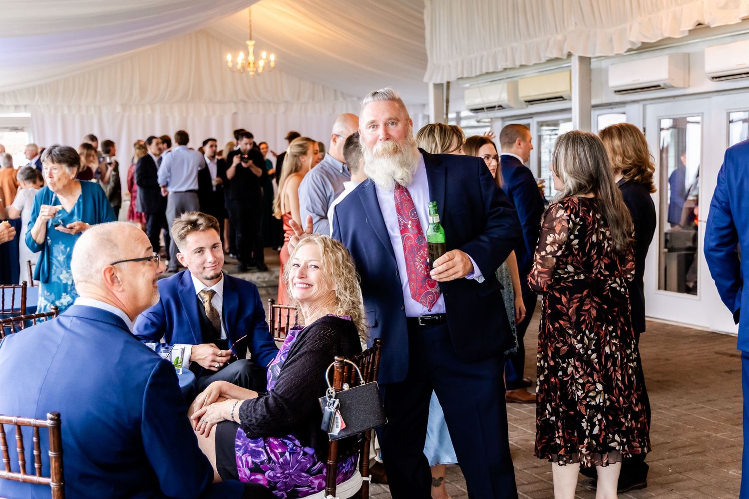 Panoramic view of wedding reception with guests socializing under draped ceiling.