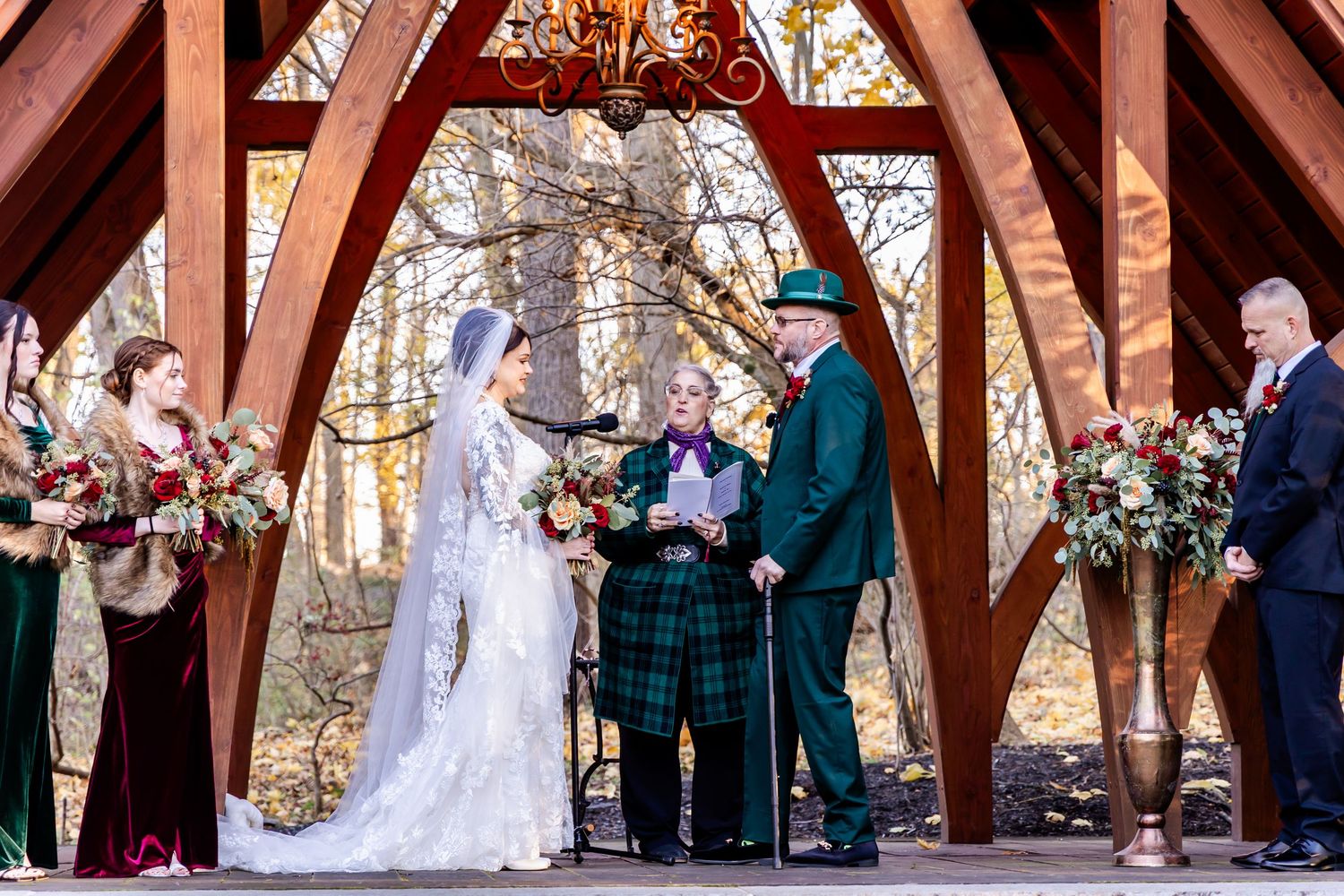 Wedding ceremony under wooden pavilion with guests gathered to witness the celebration.