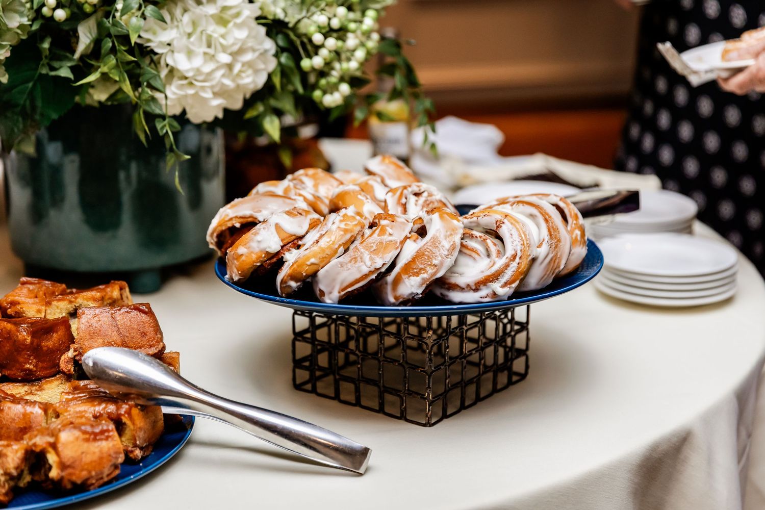 Elegant wedding reception table with white hydrangea centerpieces and pastries on display.