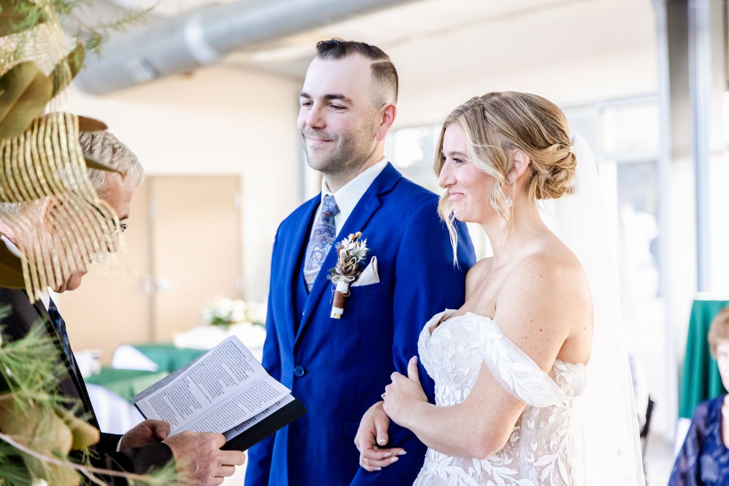 A wedding ceremony in progress with couple in white dress and blue suit.