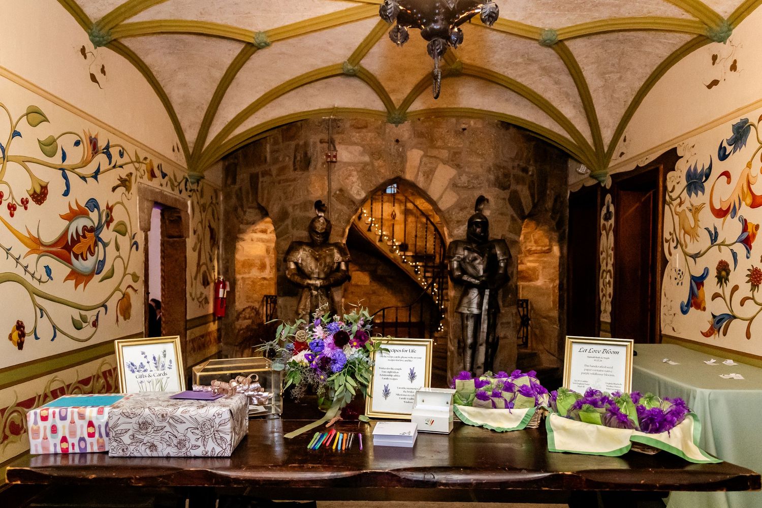 Medieval-style castle reception area with decorative table settings and purple floral arrangements.