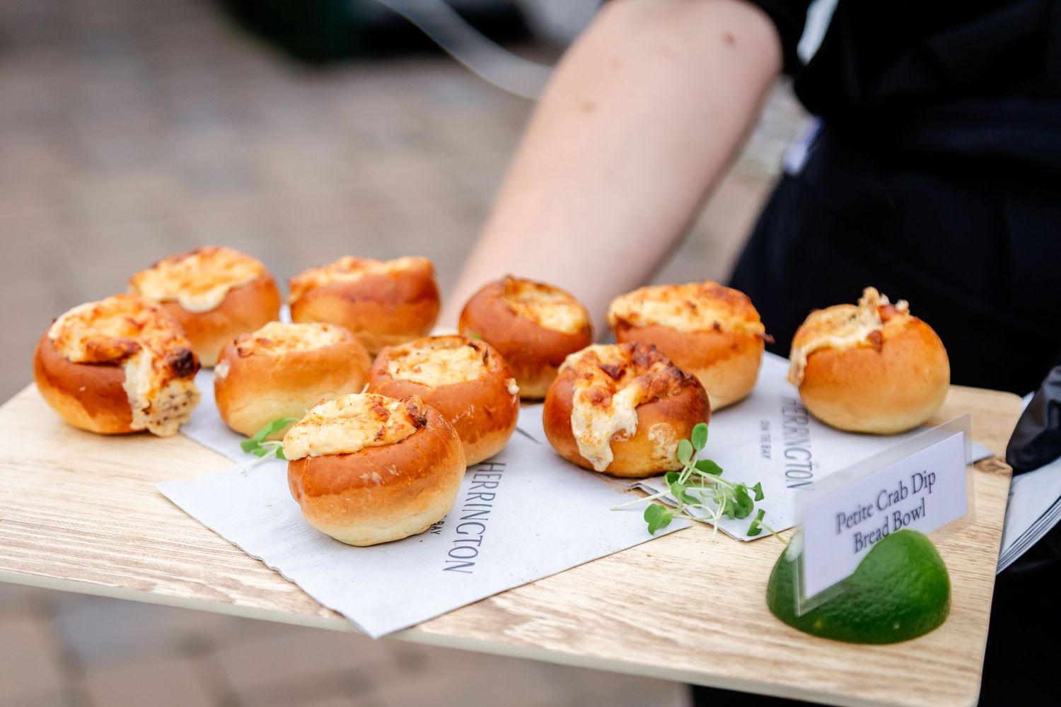 Freshly baked bagels displayed on white plates with citrus garnish at a catering event.