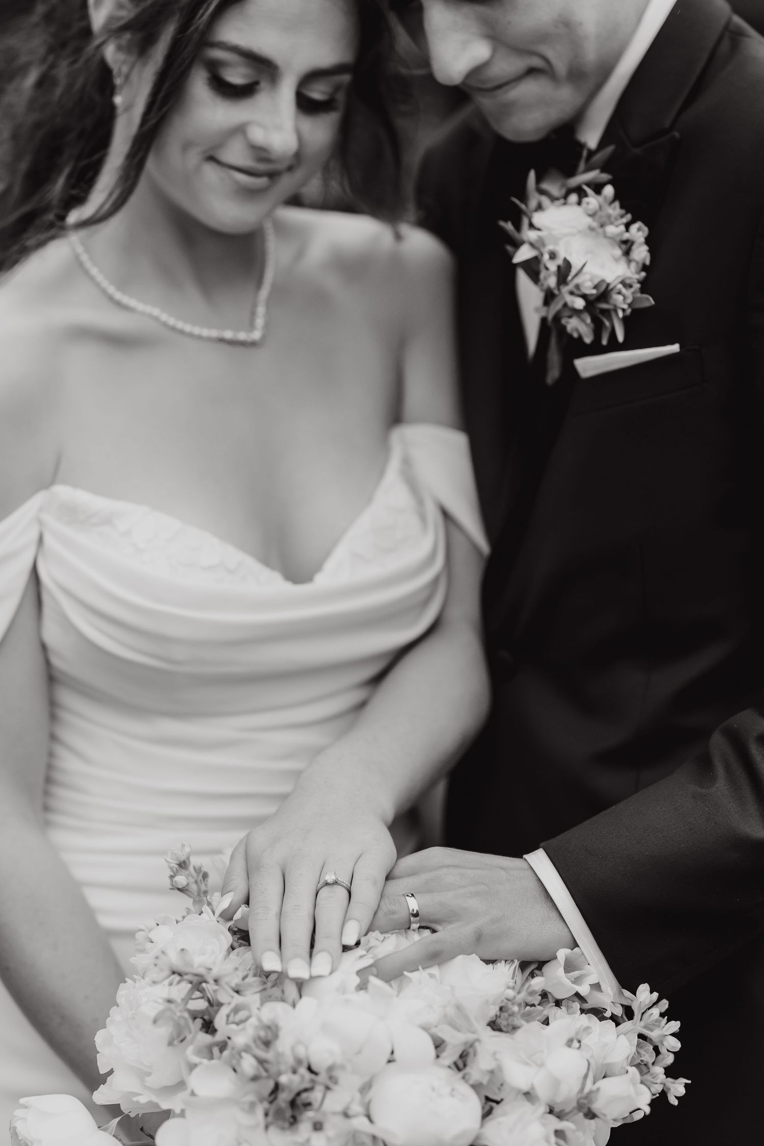 Close-up of a bride holding an elegant white floral bouquet with her engagement ring visible.