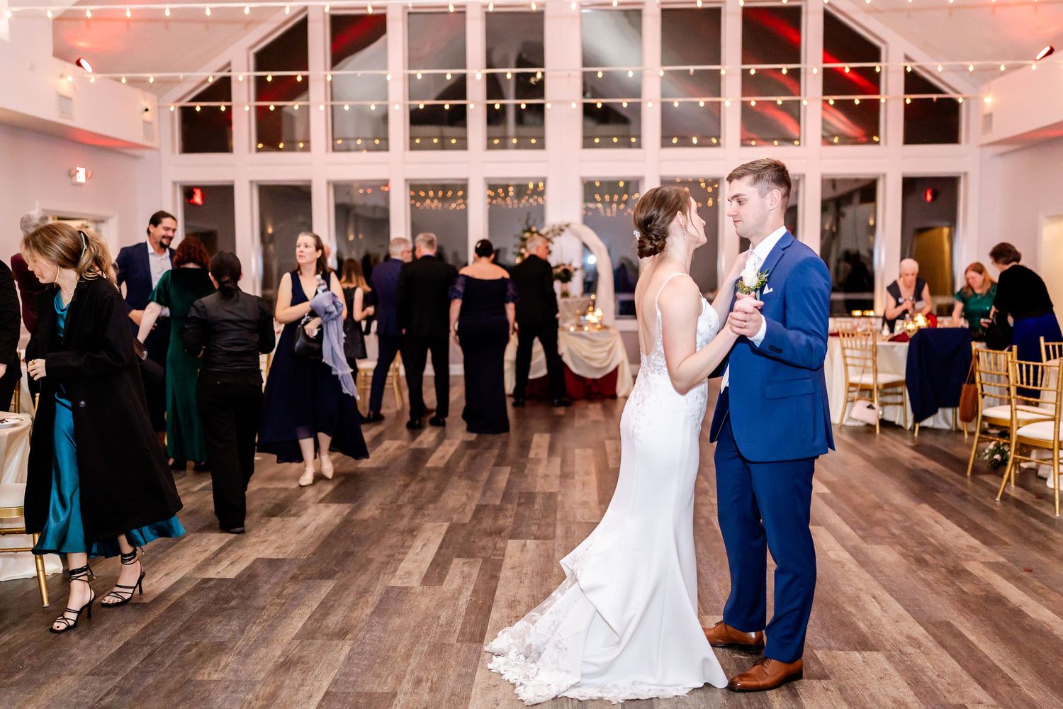 Wedding reception venue with string lights and wooden floors showing couples dancing and celebrating.