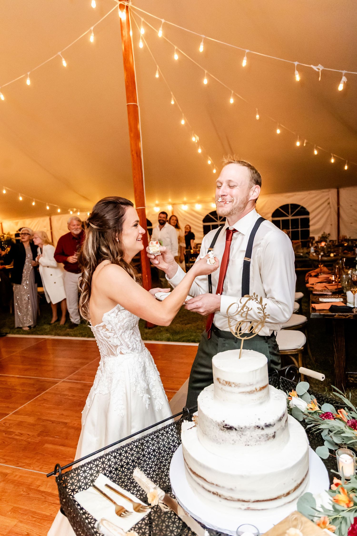 Wedding cake cutting ceremony with a classic tiered white cake under string lights.
