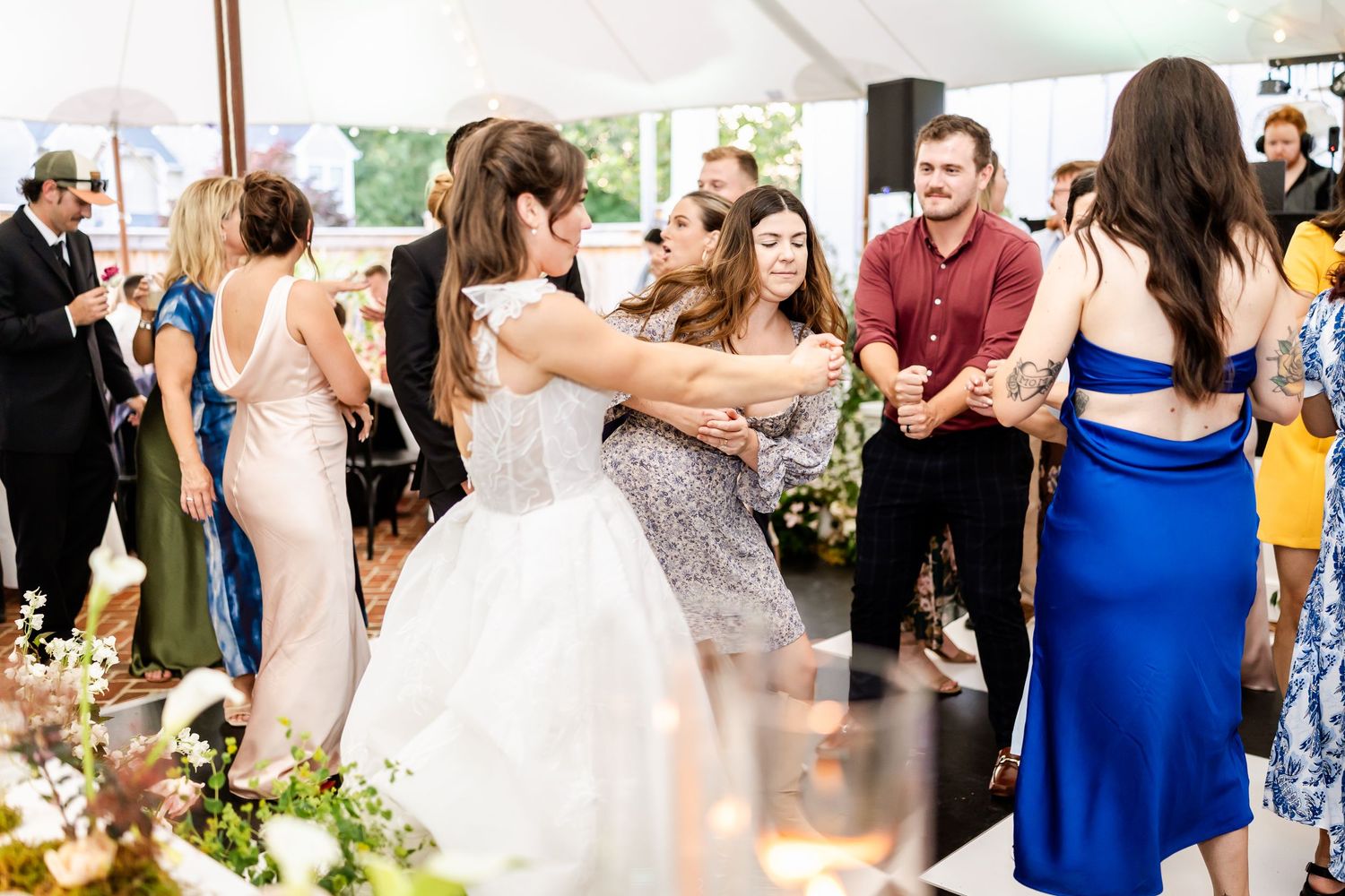 Wedding guests dancing and celebrating on the dance floor at an outdoor reception.