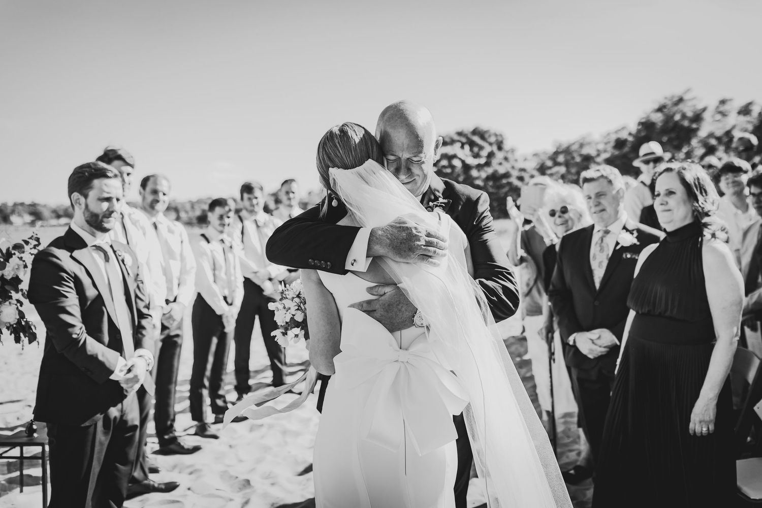 Black and white photo shows a crowd of guests standing in two lines creating an aisle for a wedding recessional.